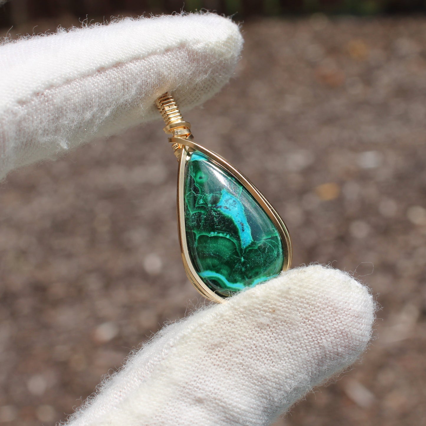 14k Gold Filled Chrysocolla Malachite teardrop pendant held with white gloves by Different Branches LLC