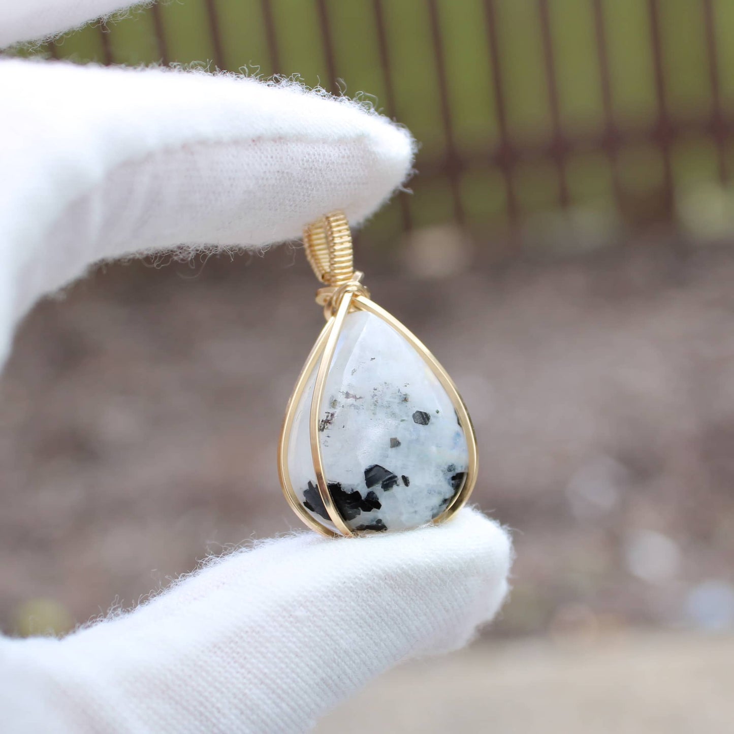 Elegant 14k gold filled jewelry featuring a teardrop pendant with black and white stone accents