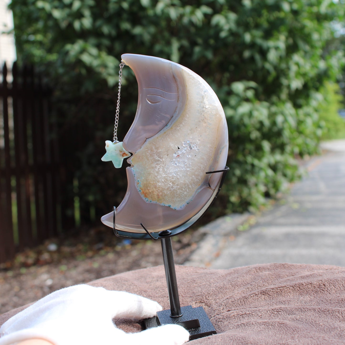 Agate Geode Moon crystal sculpture by Different Branches LLC on black stand with star charm outdoors