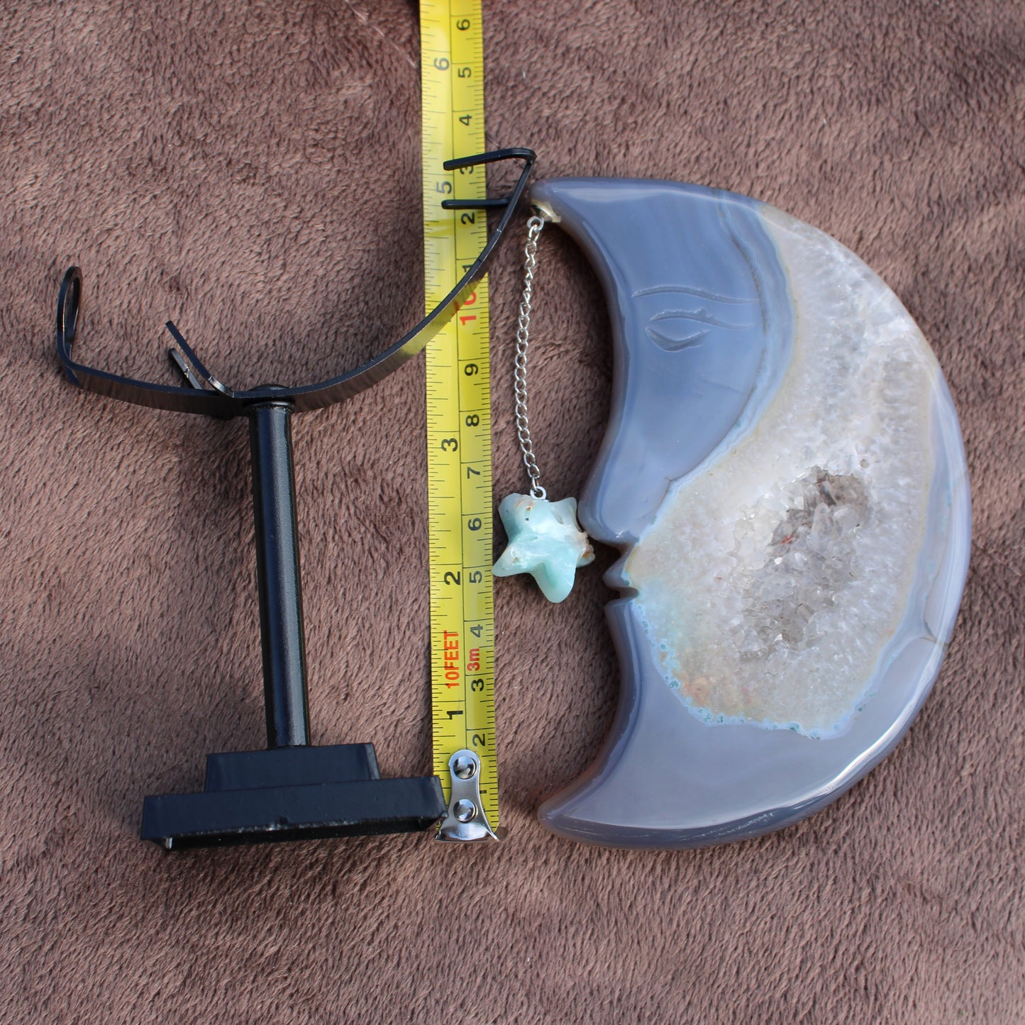 Agate Geode Moon crystal with a star charm on a chain displayed next to a black stand and measuring tape
