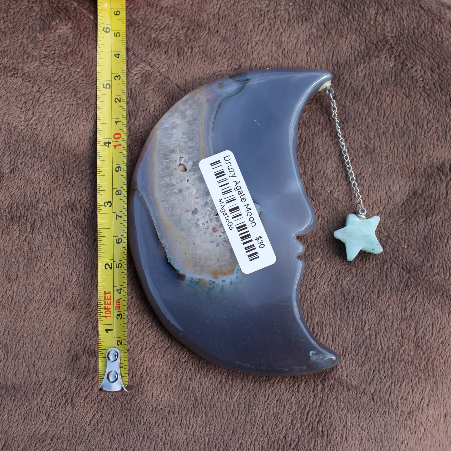 Different Branches LLC Agate Geode Moon crystal pendant with star charm and measuring tape on brown fabric