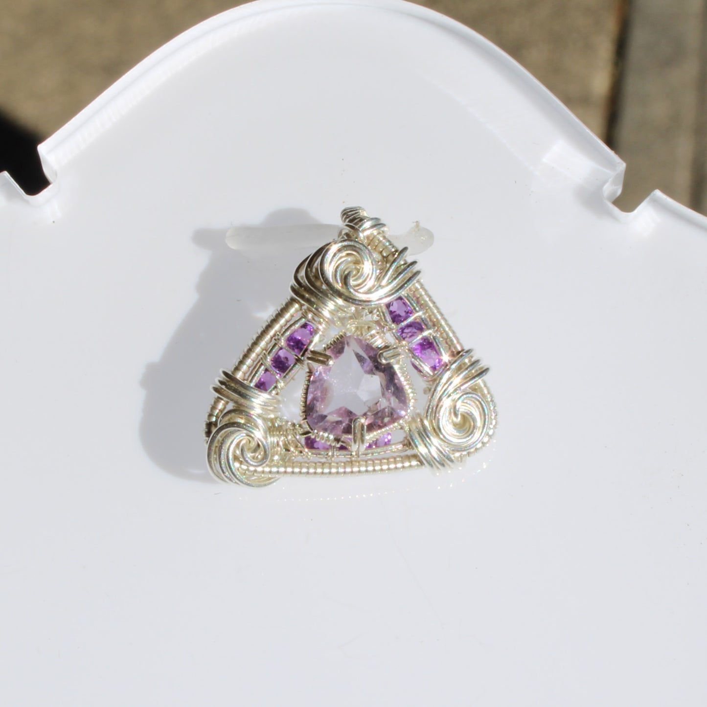 Amethyst set in sterling silver pendant with intricate wire wrapping and triangular design