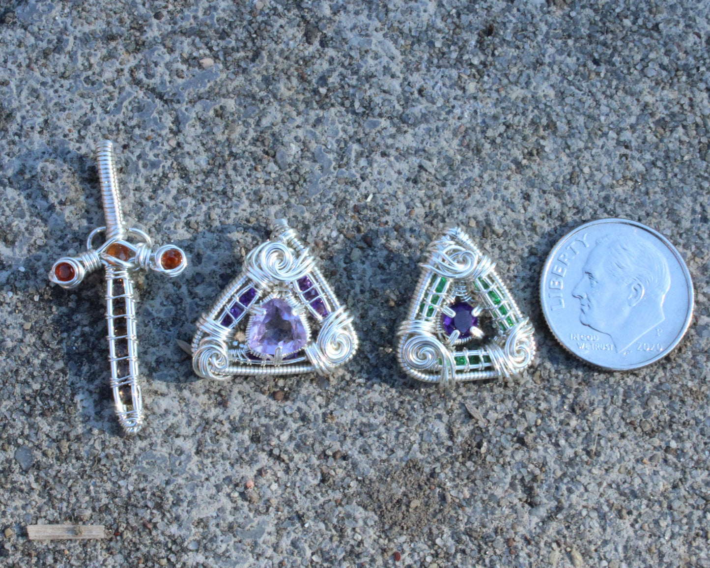 Amethyst set in sterling silver pendant with unique wire design next to a quarter for size reference