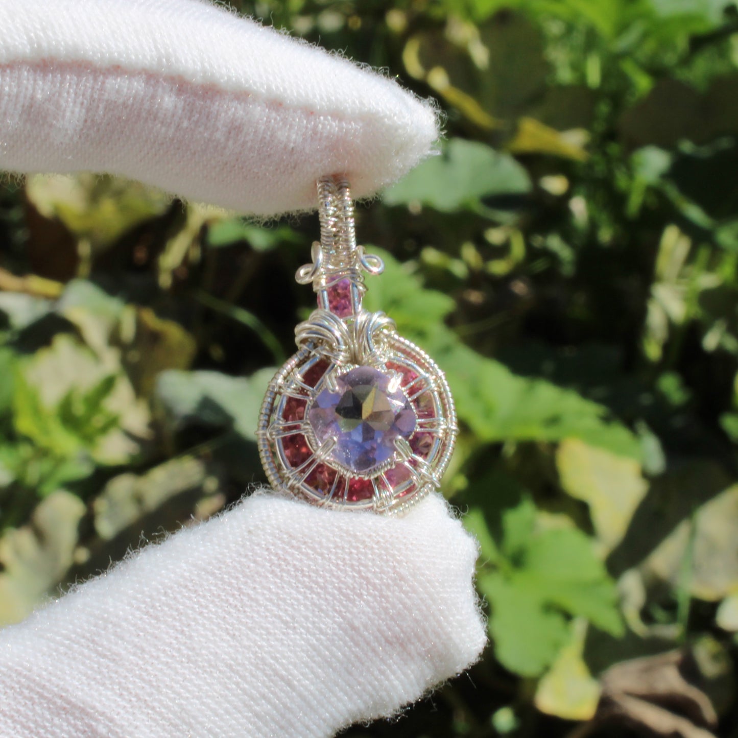 Amethyst Sterling Silver pendant with intricate design and pink tourmaline accents held by a gloved hand