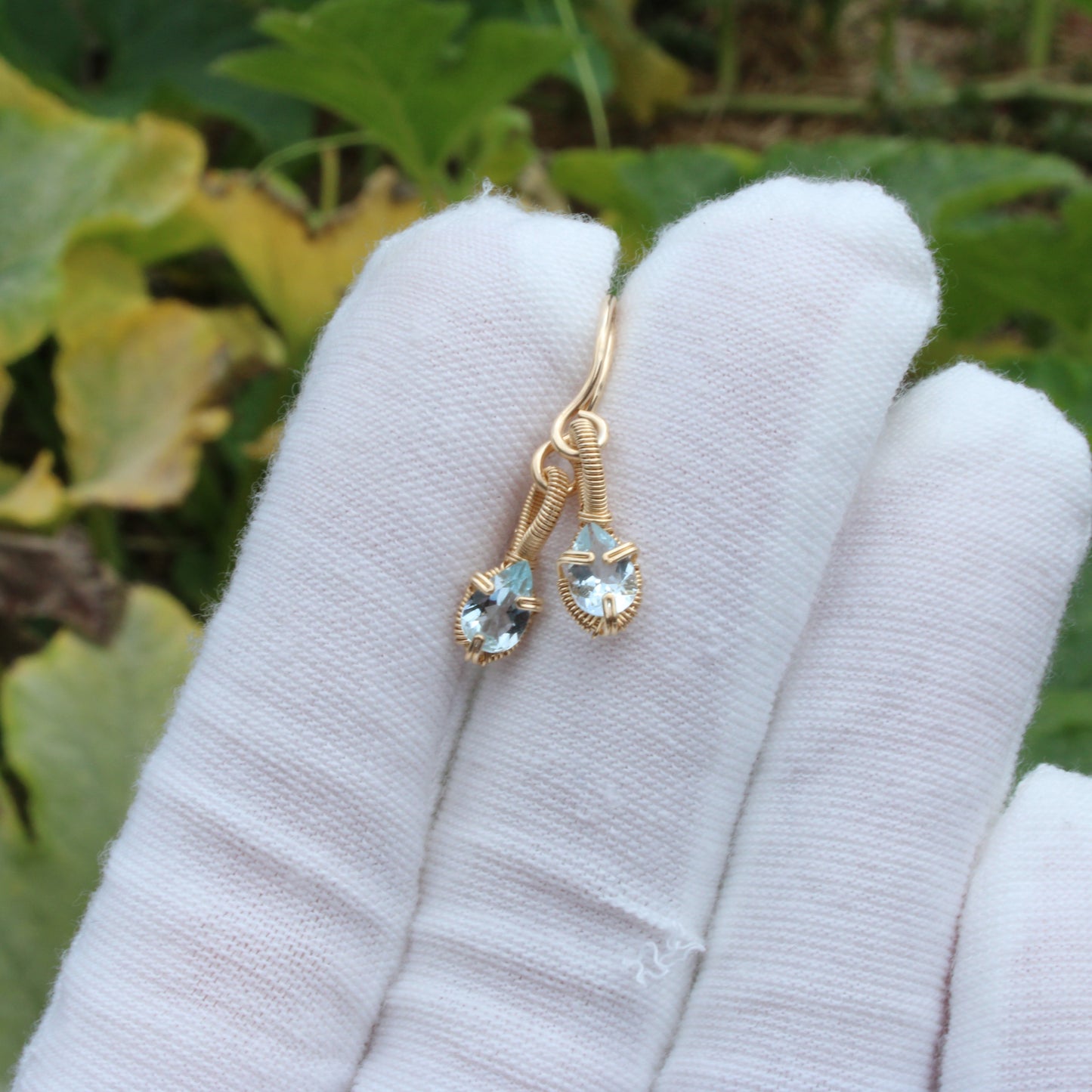Aquamarine gold fill earrings displayed elegantly on a hand with a soft background