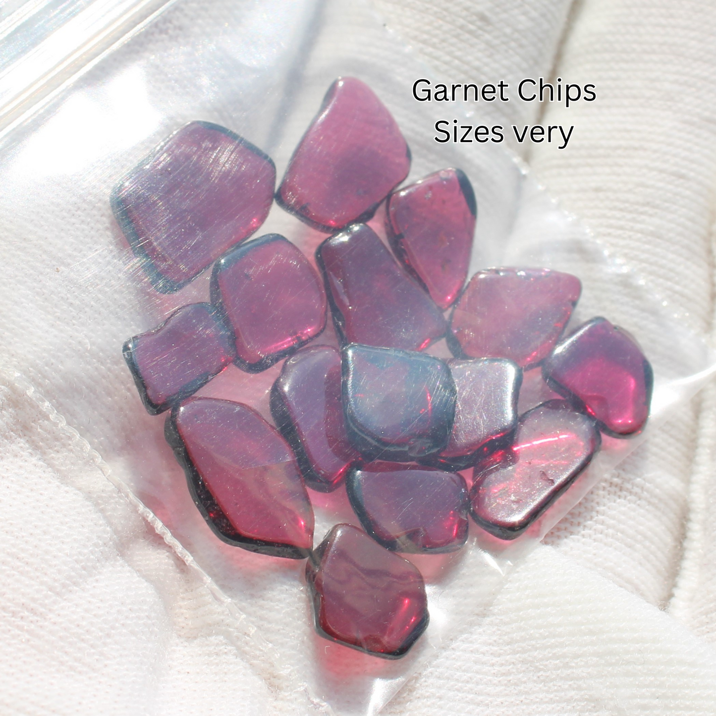 Bag of deep red garnet chips for jewelry making displayed on glove for Made to order rings