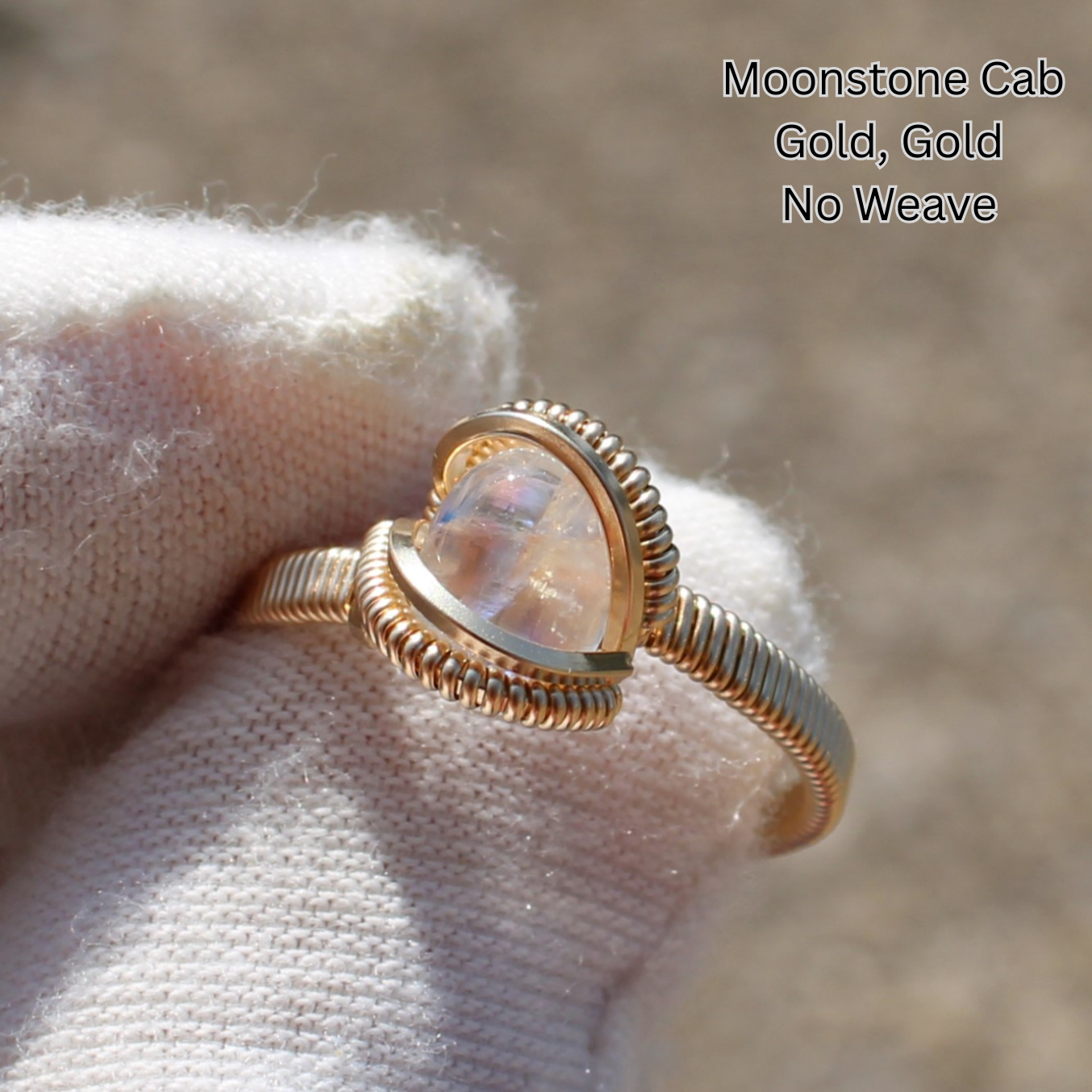 Gold wire wrapped moonstone cabochon ring held in white glove by Different Branches LLC Made to order rings