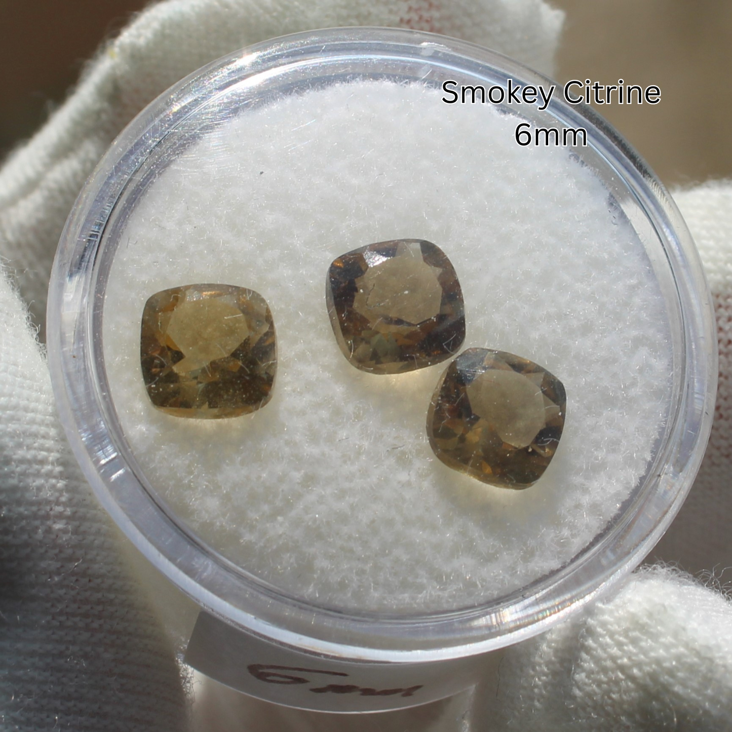 Three 6mm smokey citrine cushion gemstones in clear display for Made to order rings