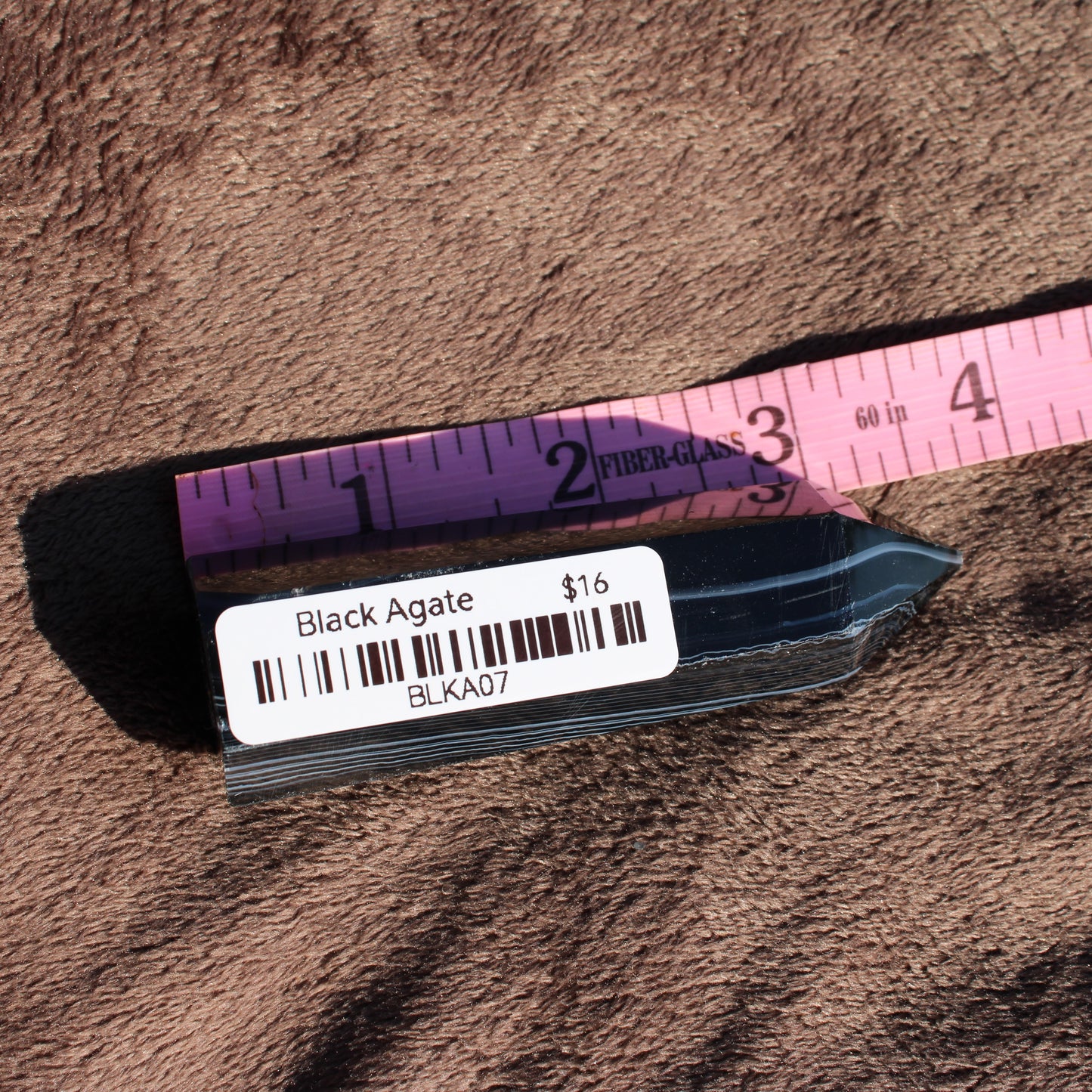 Black Agate Tower Collection featuring a polished dark crystal with a measuring tape for size reference