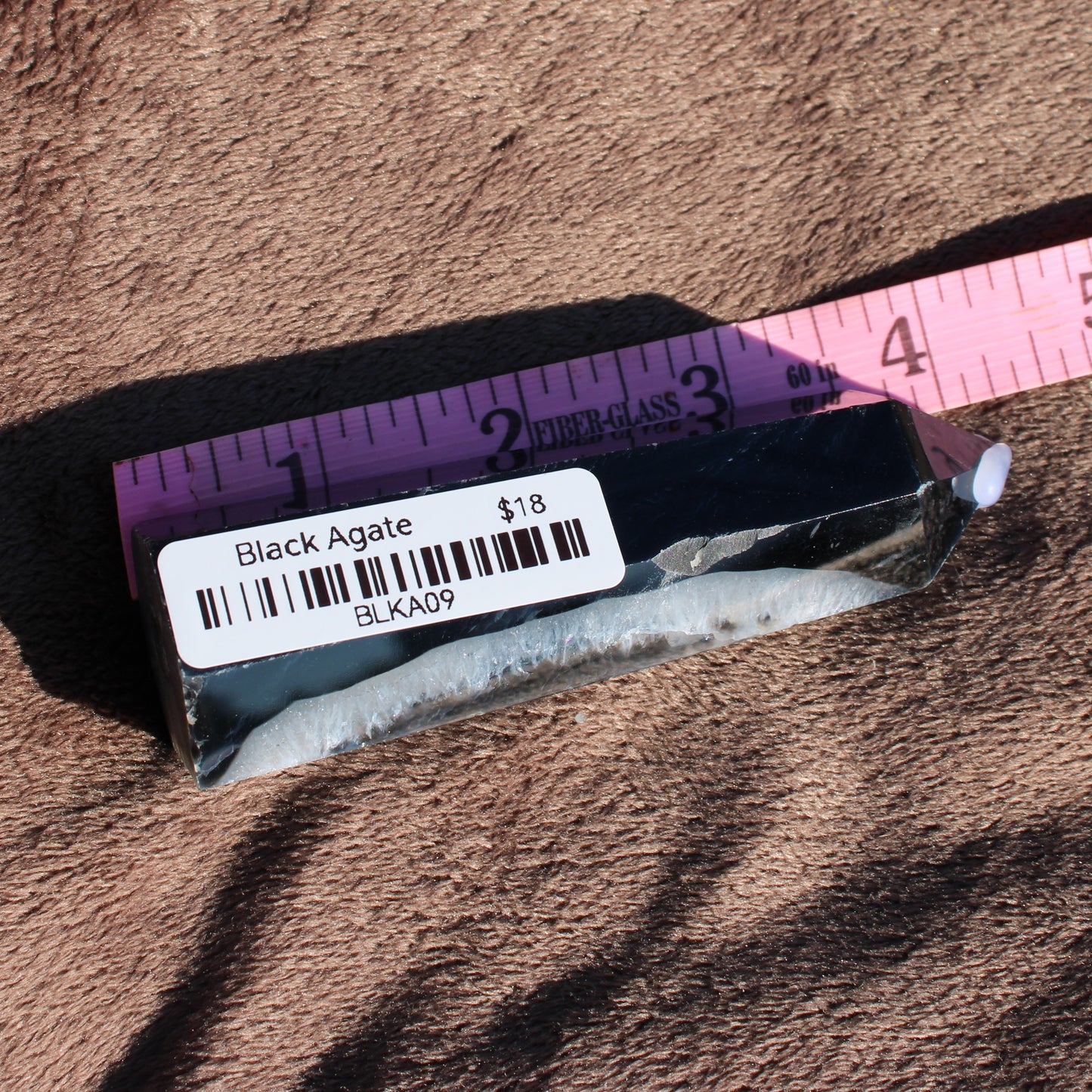 Black Agate tower collection piece displayed on a soft surface with a ruler for size reference