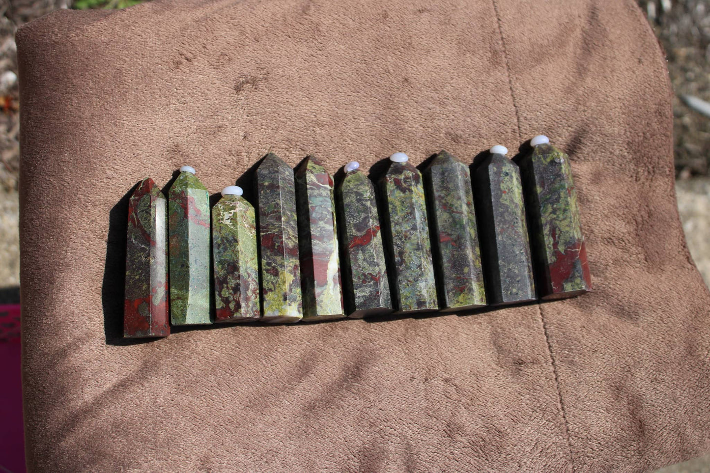 Set of Bloodstone tower crystal pieces showcasing unique green and red patterns on a soft surface