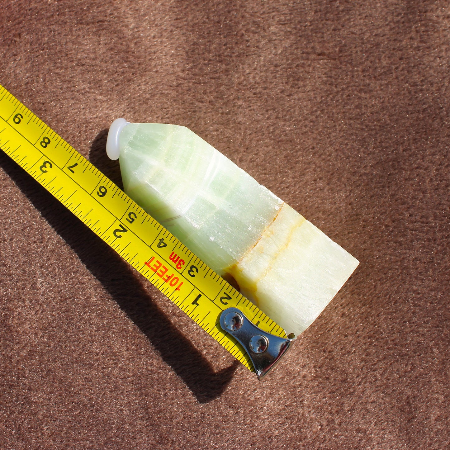 Calcite Tower crystal measuring approximately 3 inches with a pointed tip on brown fabric