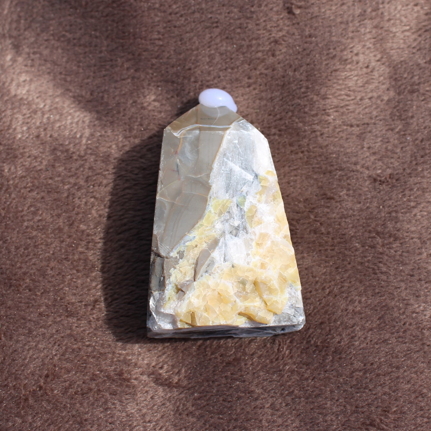 Calcite Tower crystal with yellow and white natural formations on brown textured background