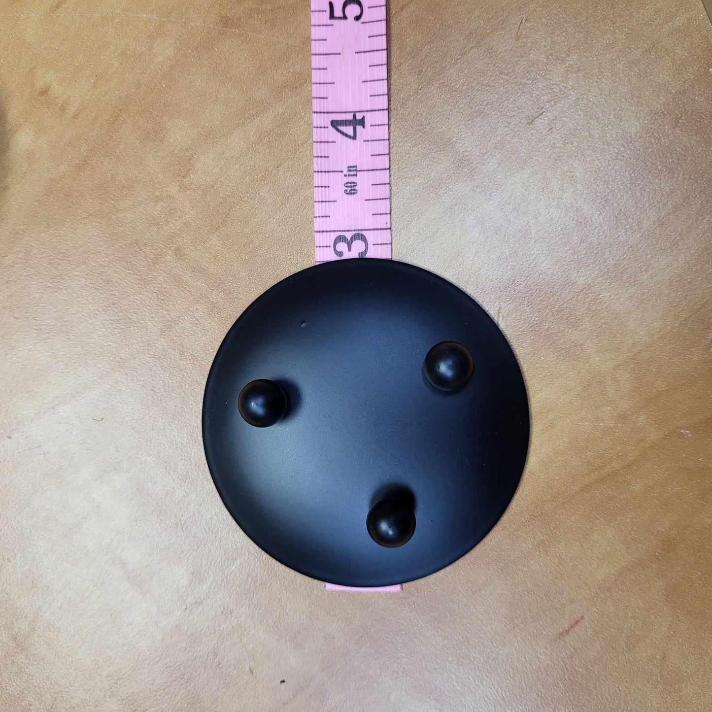Black candle dish with three feet for stability, ideal for displaying candles elegantly