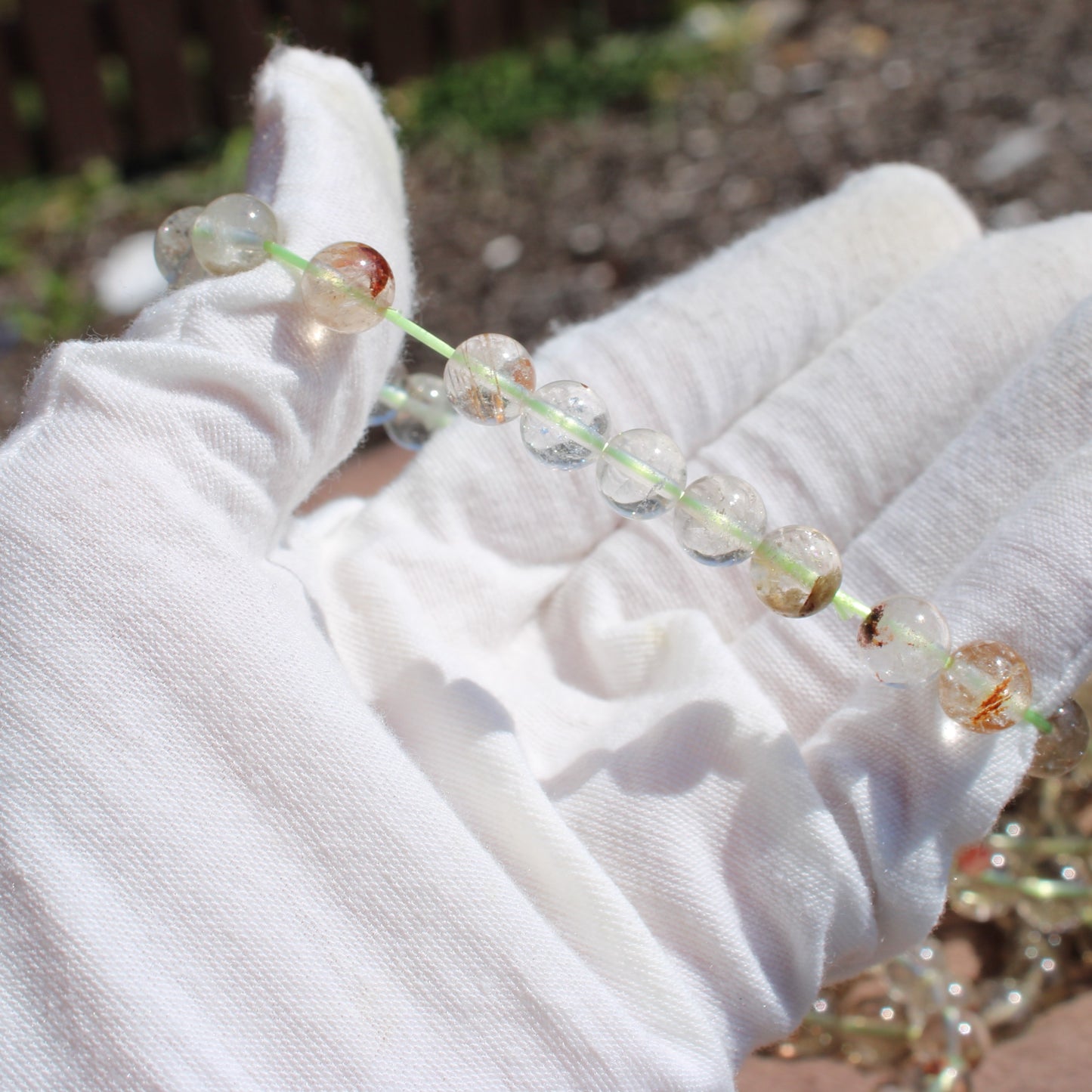 Hand holding a Clear Quartz Bracelet featuring shimmering beads and natural inclusions