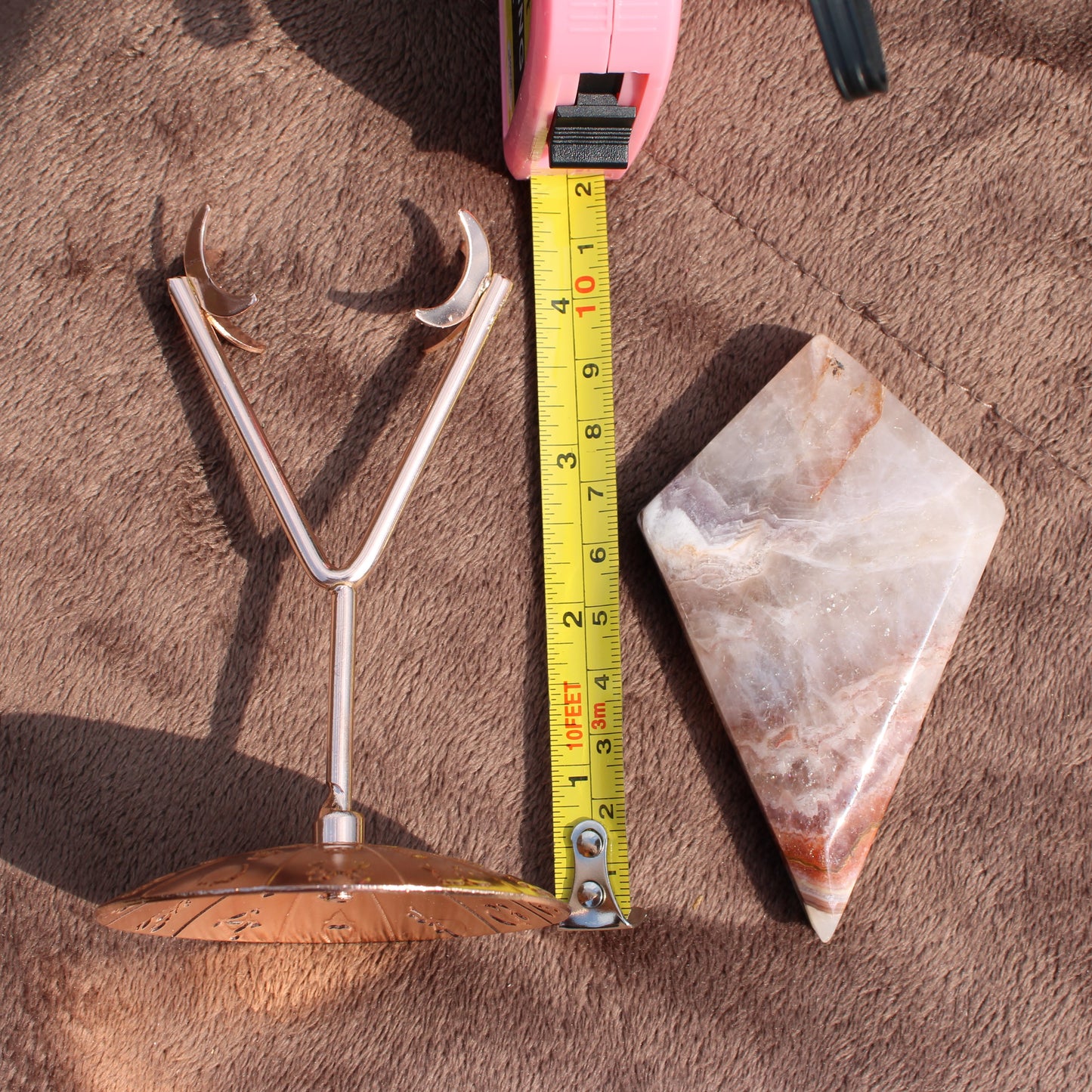 Crazy Lace Agate Diamond crystal with metal stand and measuring tape on brown fabric surface