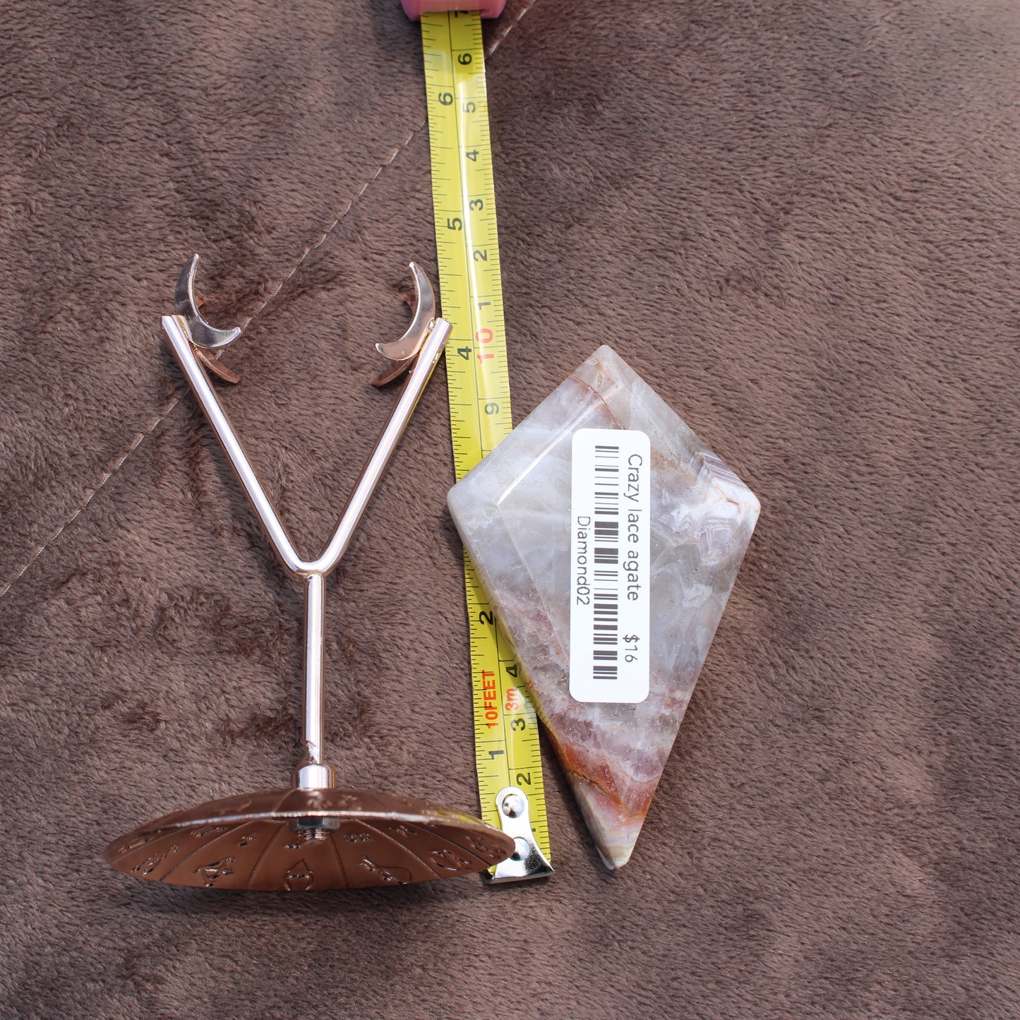 Crazy Lace Agate Diamond crystal from Different Branches LLC placed next to a measuring tape and metal stand