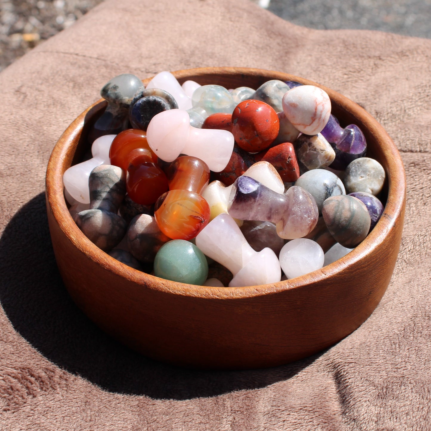 Assorted polished gemstones in a bowl featuring a variety of Crystal Mushroom Carving shapes and colors