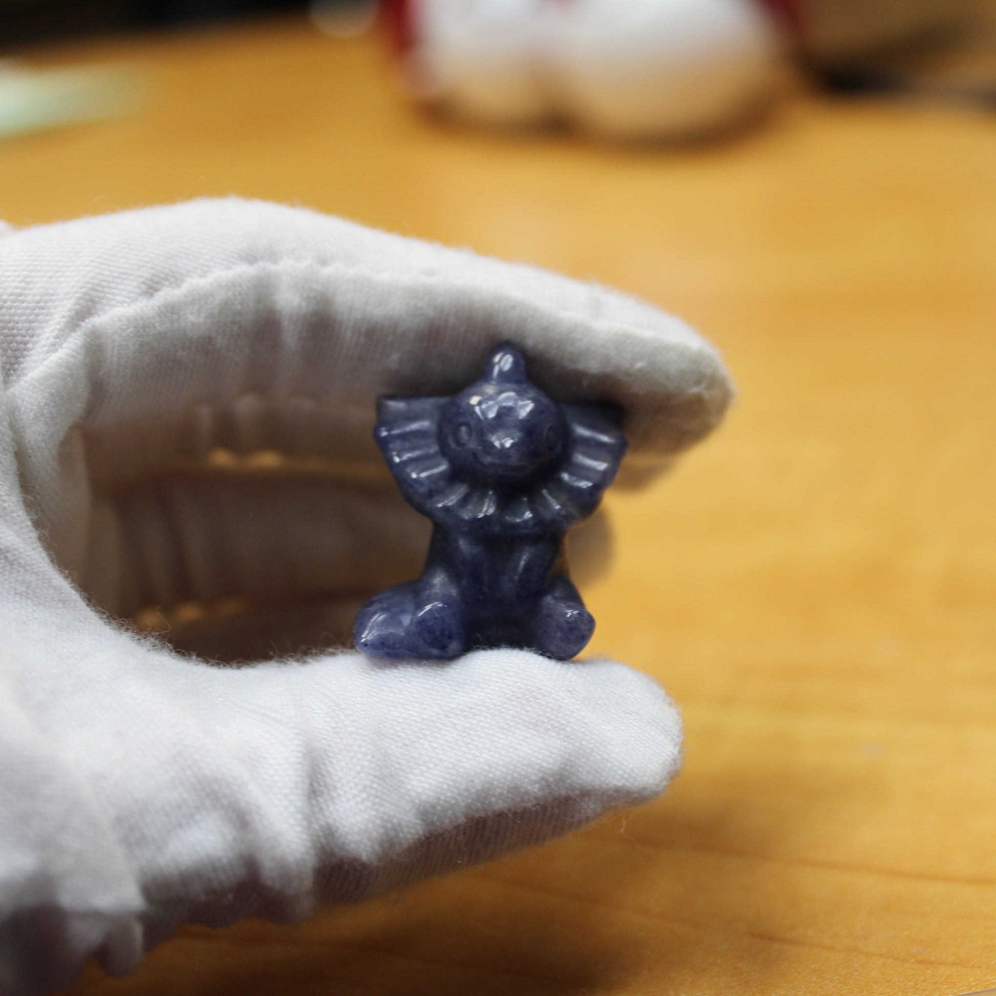 Small blue crystal Pokémon figurine held by hand wearing white glove from crystal pokemon gift set