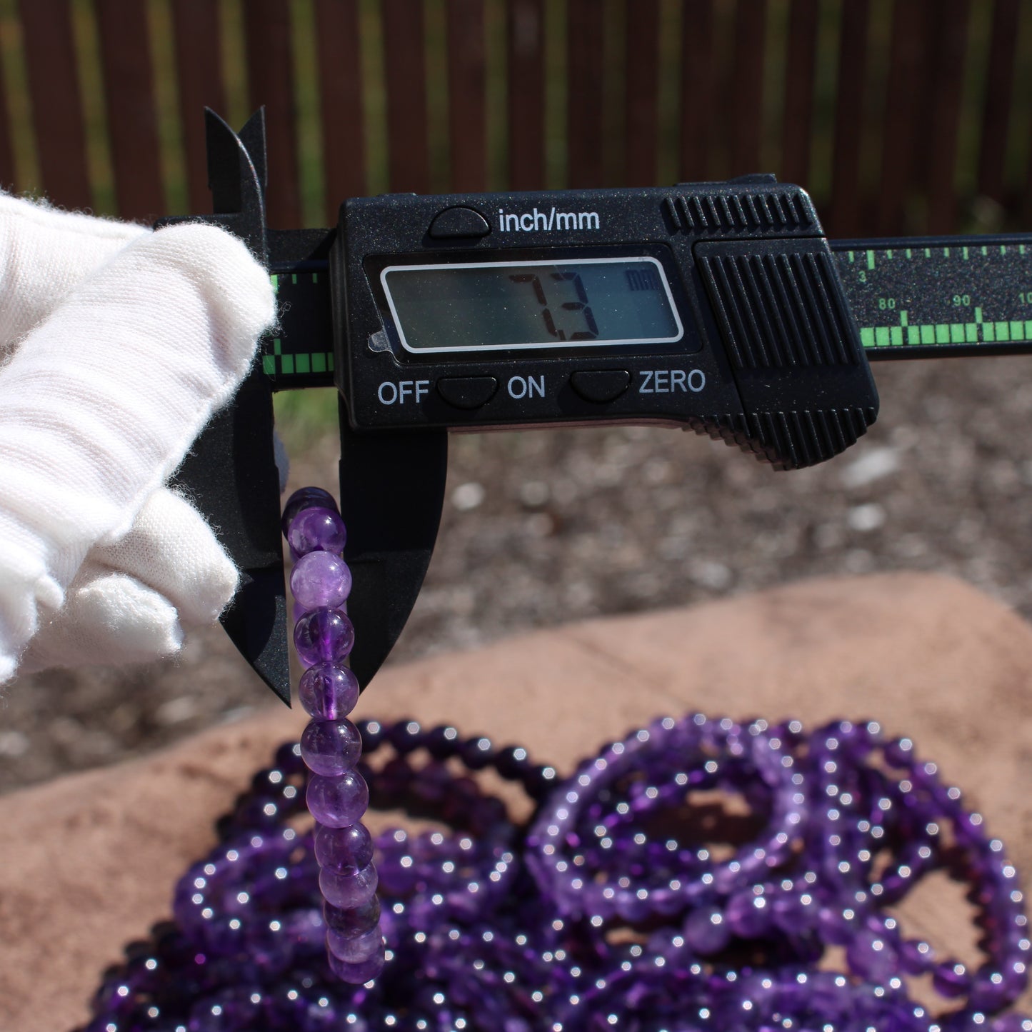Measuring a Deep Purple Amethyst Bracelet with a caliper for size accuracy