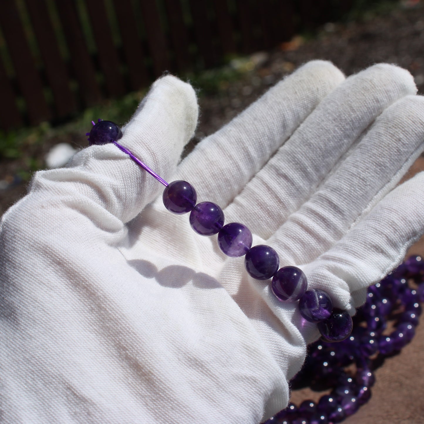 Hand holding a Deep Purple Amethyst Bracelet showcasing its beautiful gemstones and craftsmanship