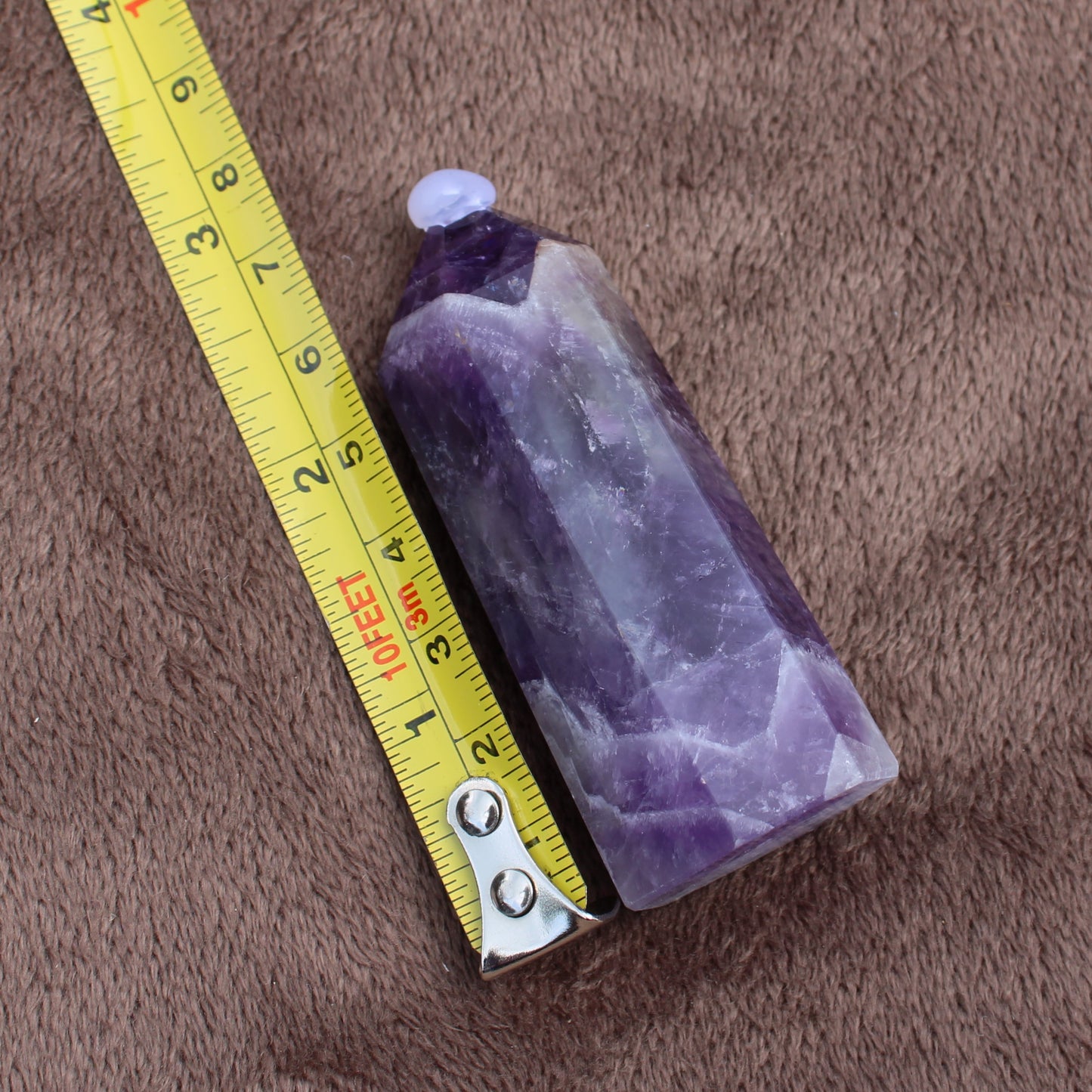 Dream Amethyst Tower crystal measuring about 4 inches long on a brown fabric background
