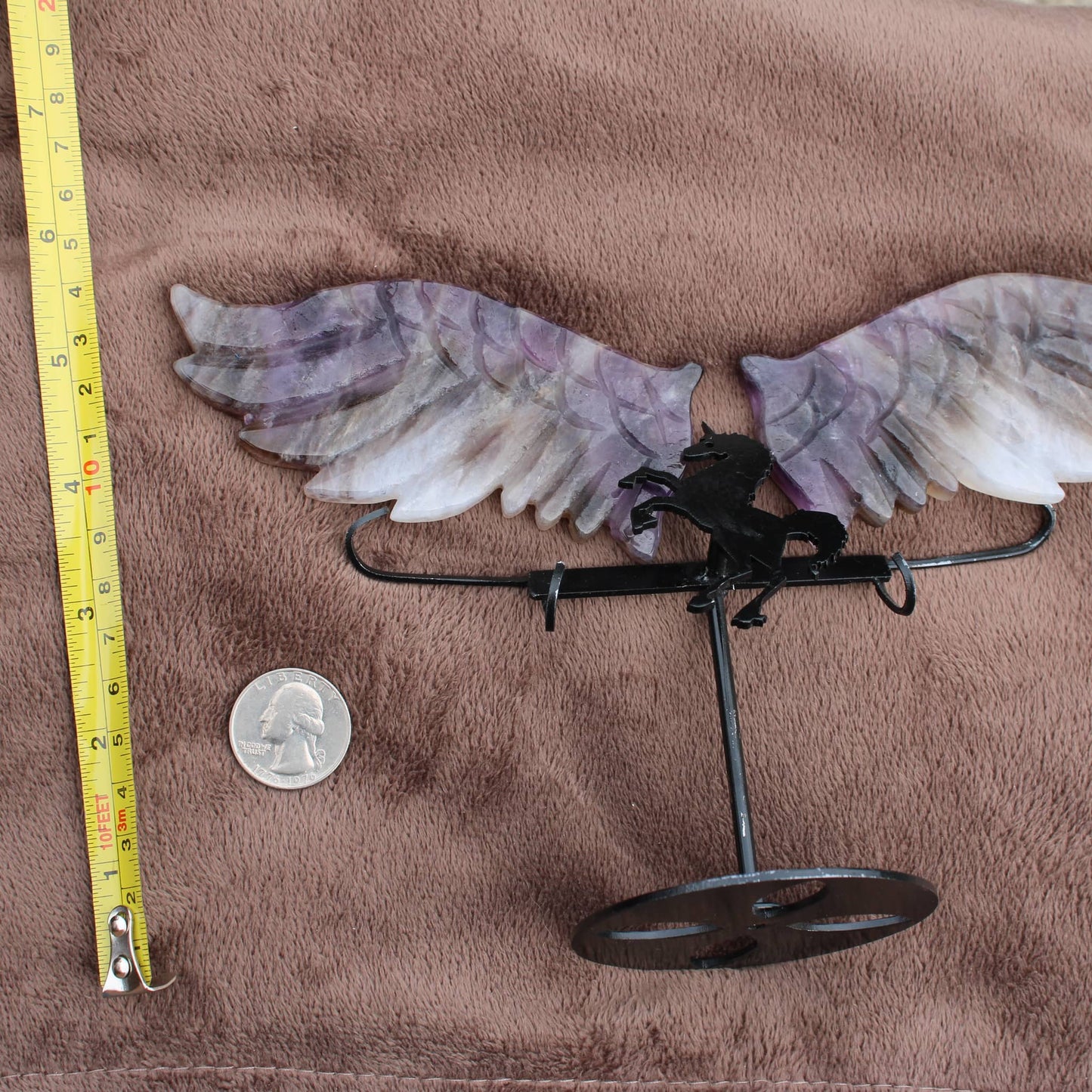 Dream Amethyst Unicorn Wings crystal display with purple and white wings on metal stand next to measuring tape and quarter