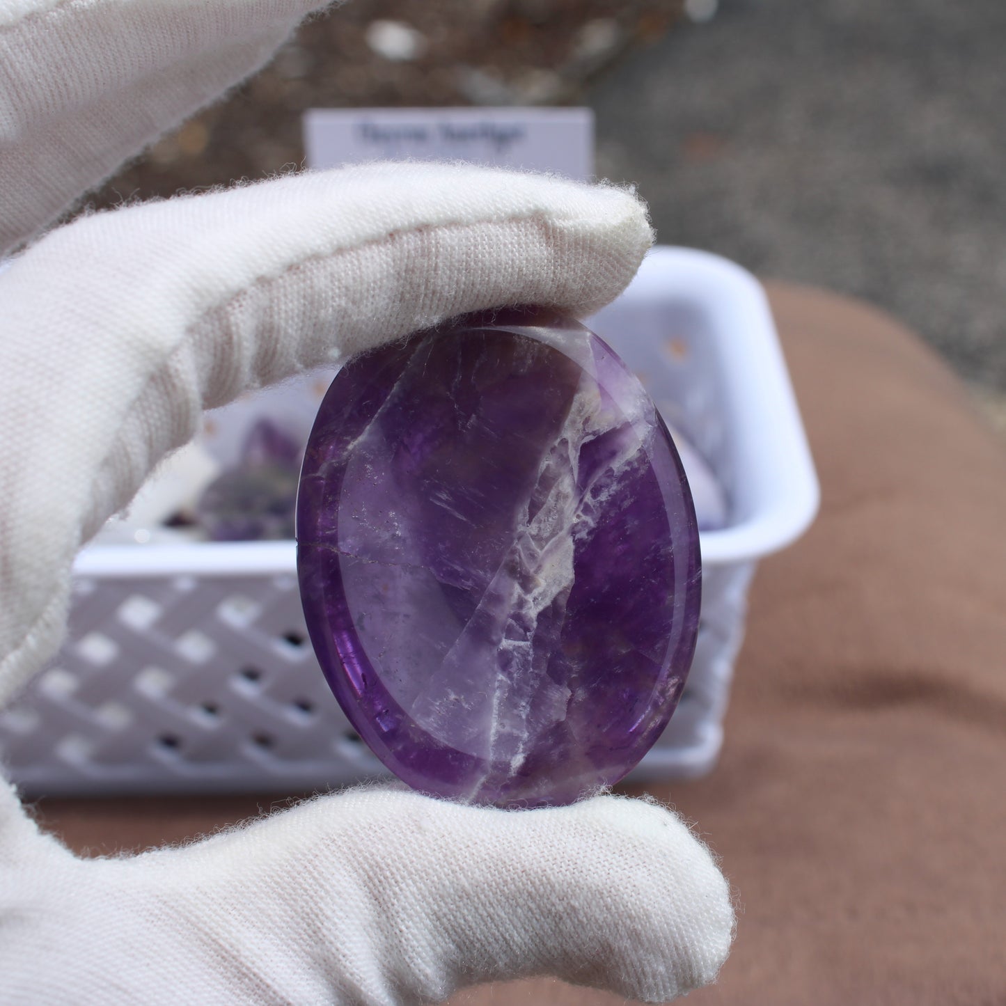Hand holding a polished purple Dream Amethyst Worry Stone crystal by Different Branches LLC