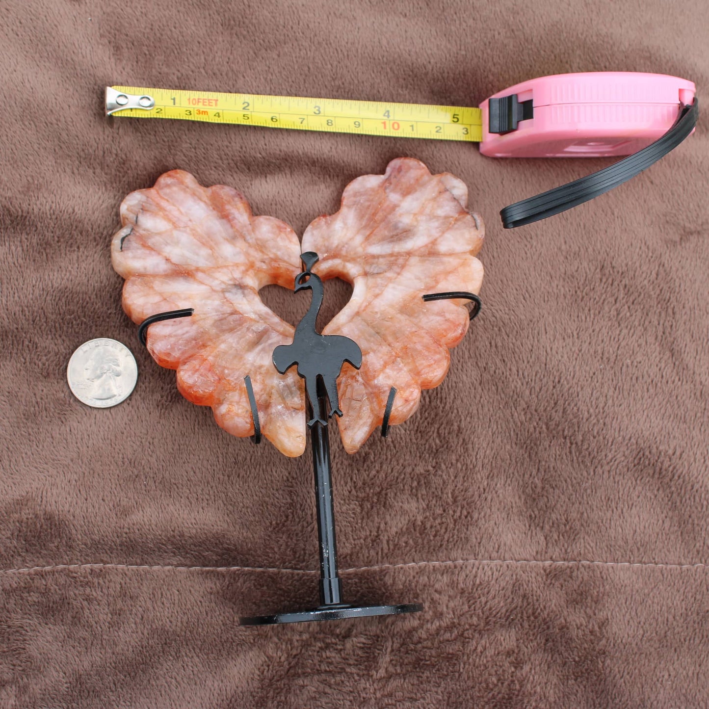 Fire Quartz Peacock Wings crystal on black metal stand with measuring tape and quarter for size