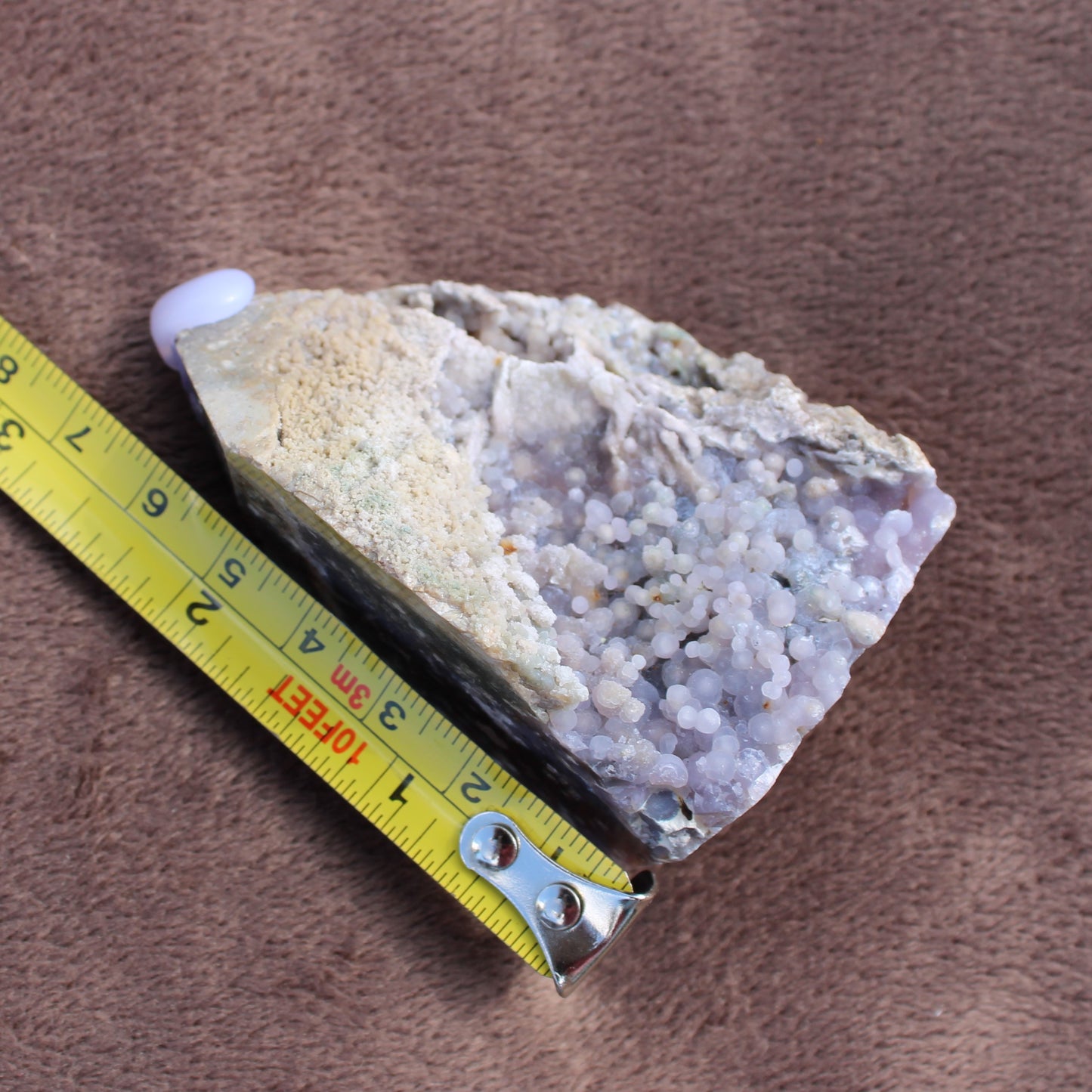 Grape Agate Tower crystal with light purple botryoidal formations next to a measuring tape showing size