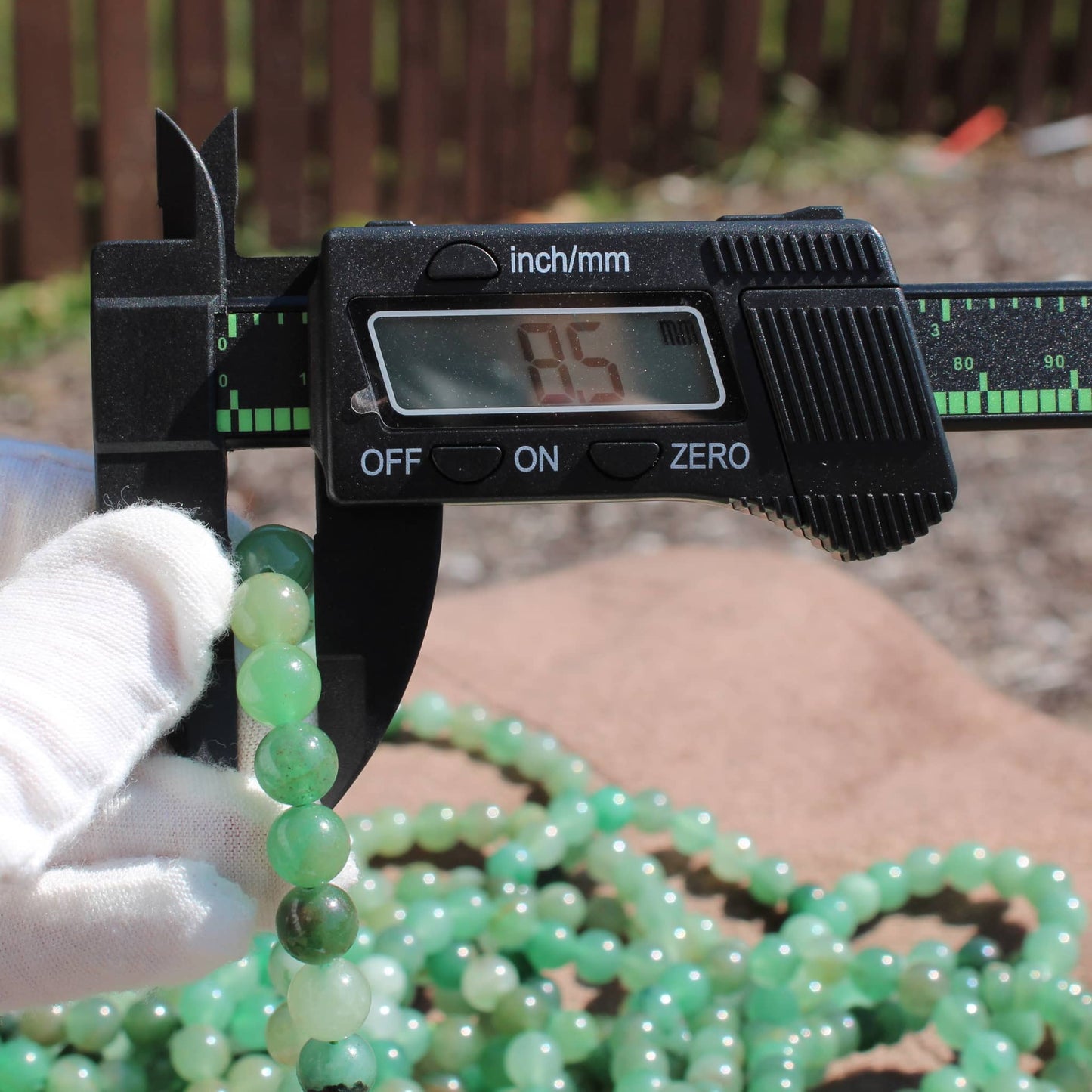 Measuring a Green Aventurine Bracelet beads with calipers for size accuracy