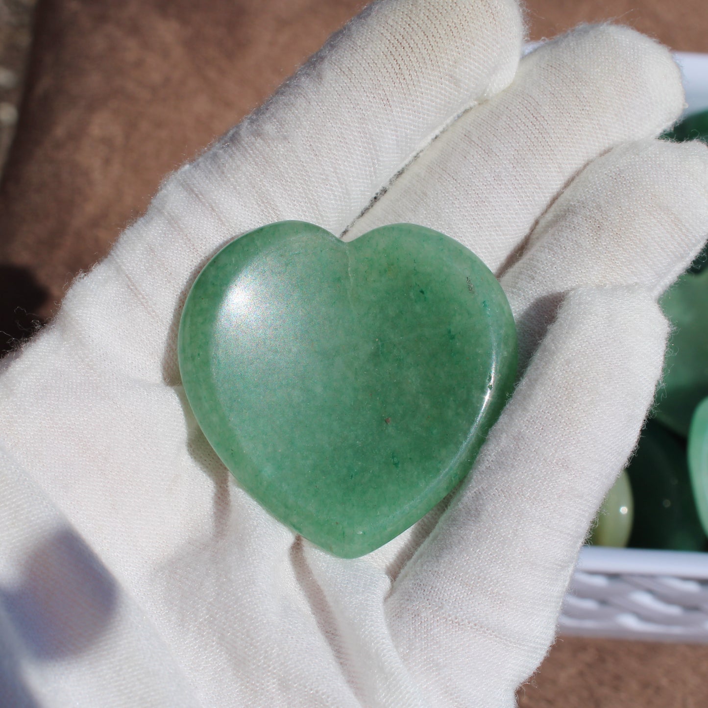Heart-shaped Green Aventurine Worry Stone held in a gloved hand for relaxation and stress relief