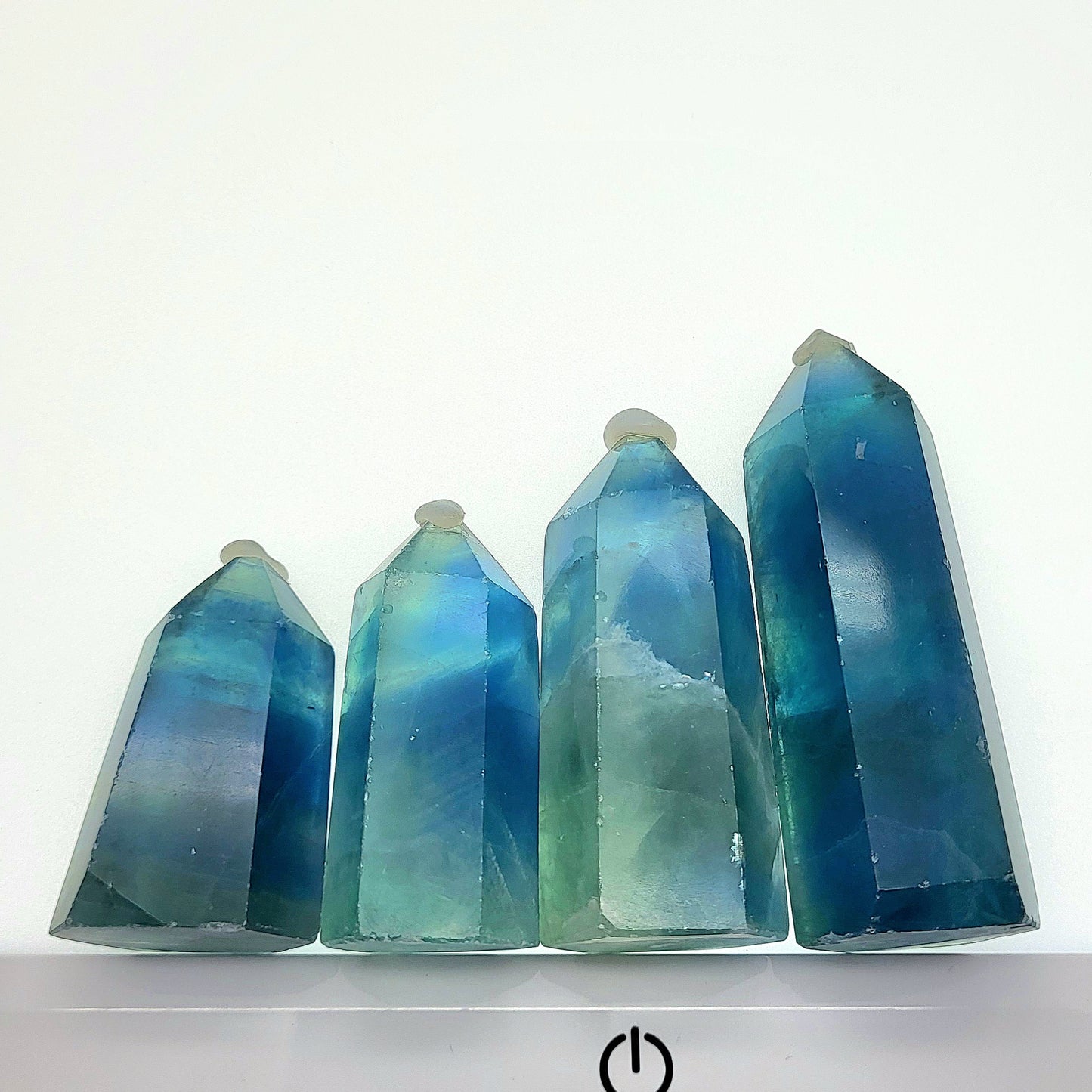 Four green fluorite tower crystals showcasing unique colors and polished surfaces for healing and decoration