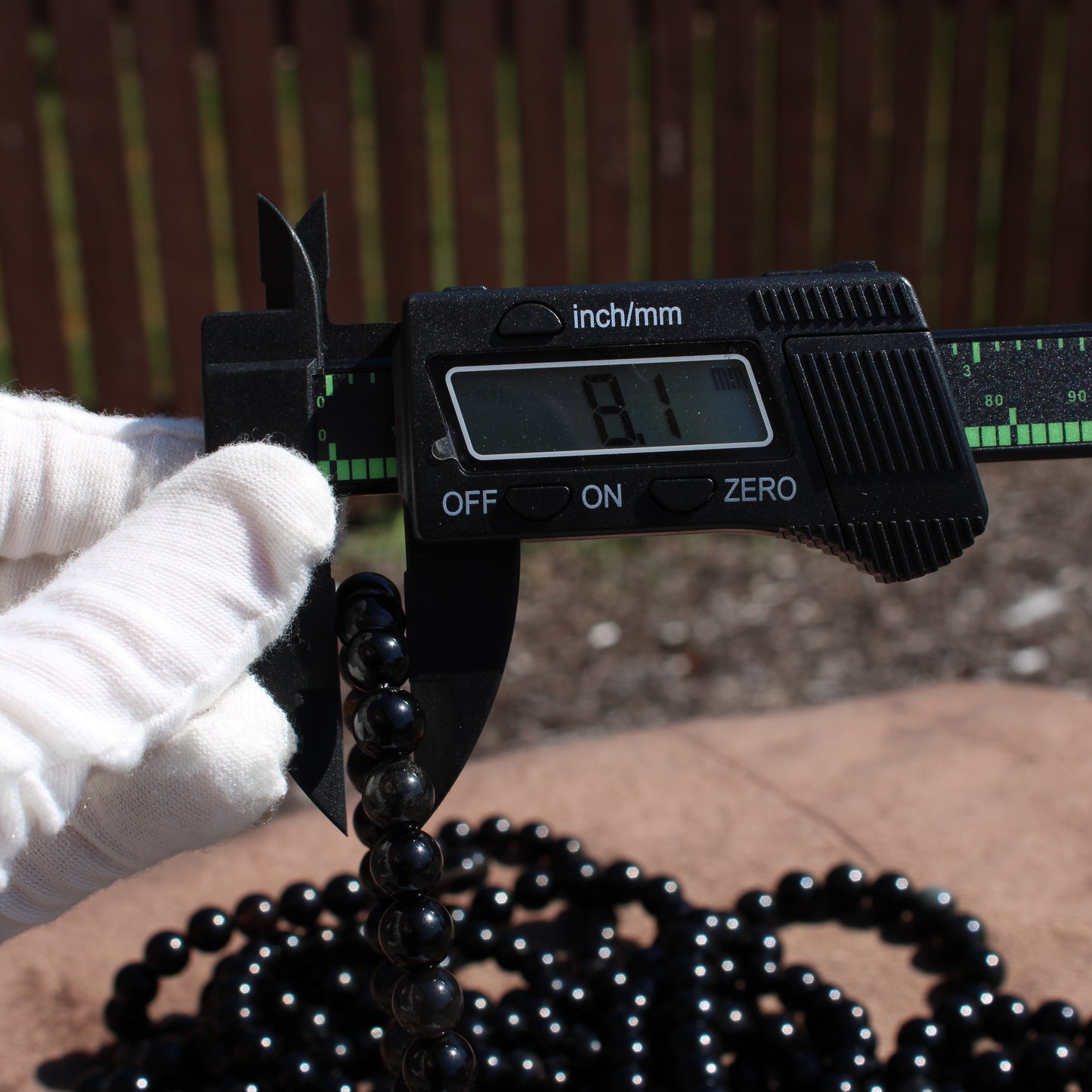 Measuring a handmade obsidian bracelet with a caliper for accurate sizing and detailed craftsmanship