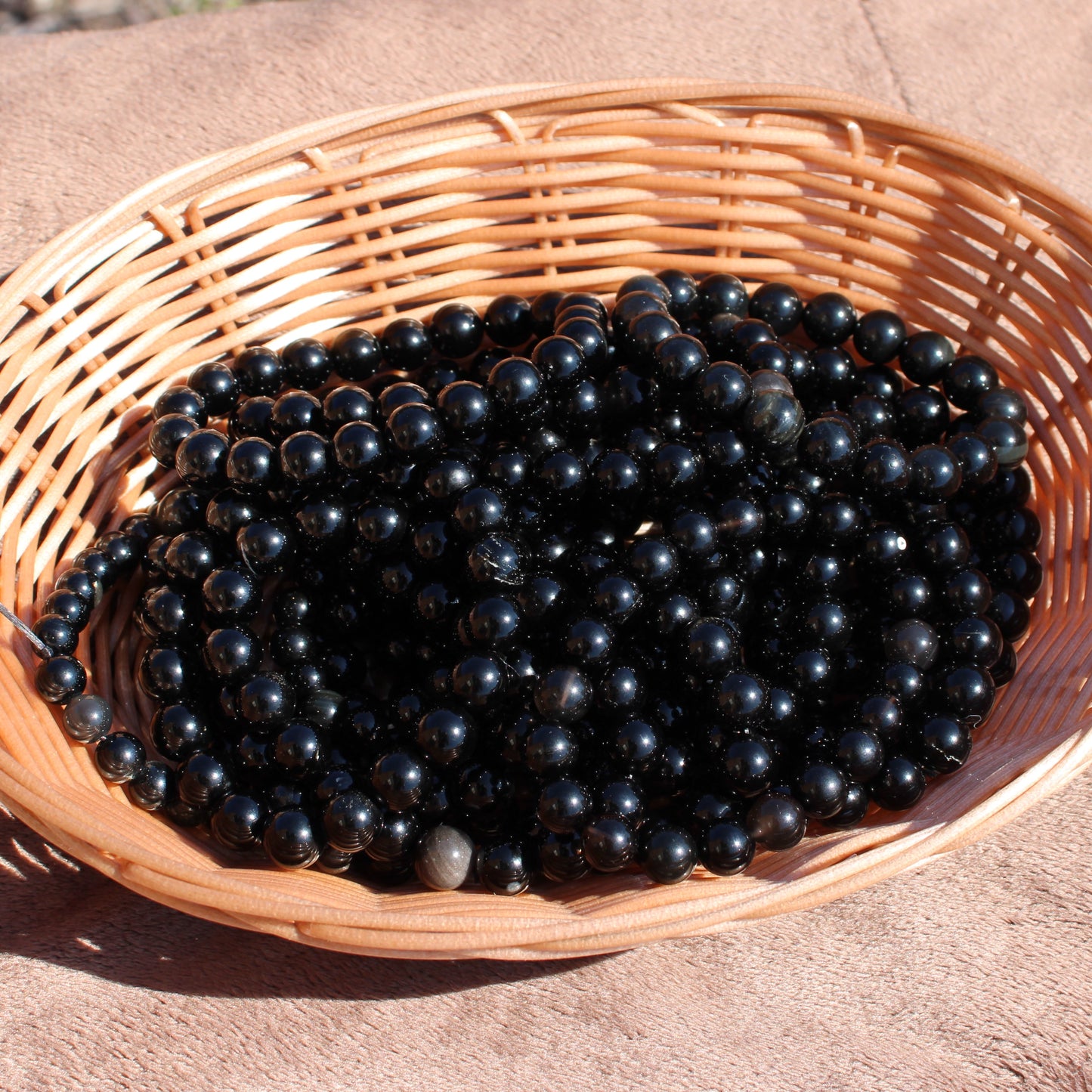 Handmade obsidian bracelet displayed in a woven basket showcasing its glossy black finish