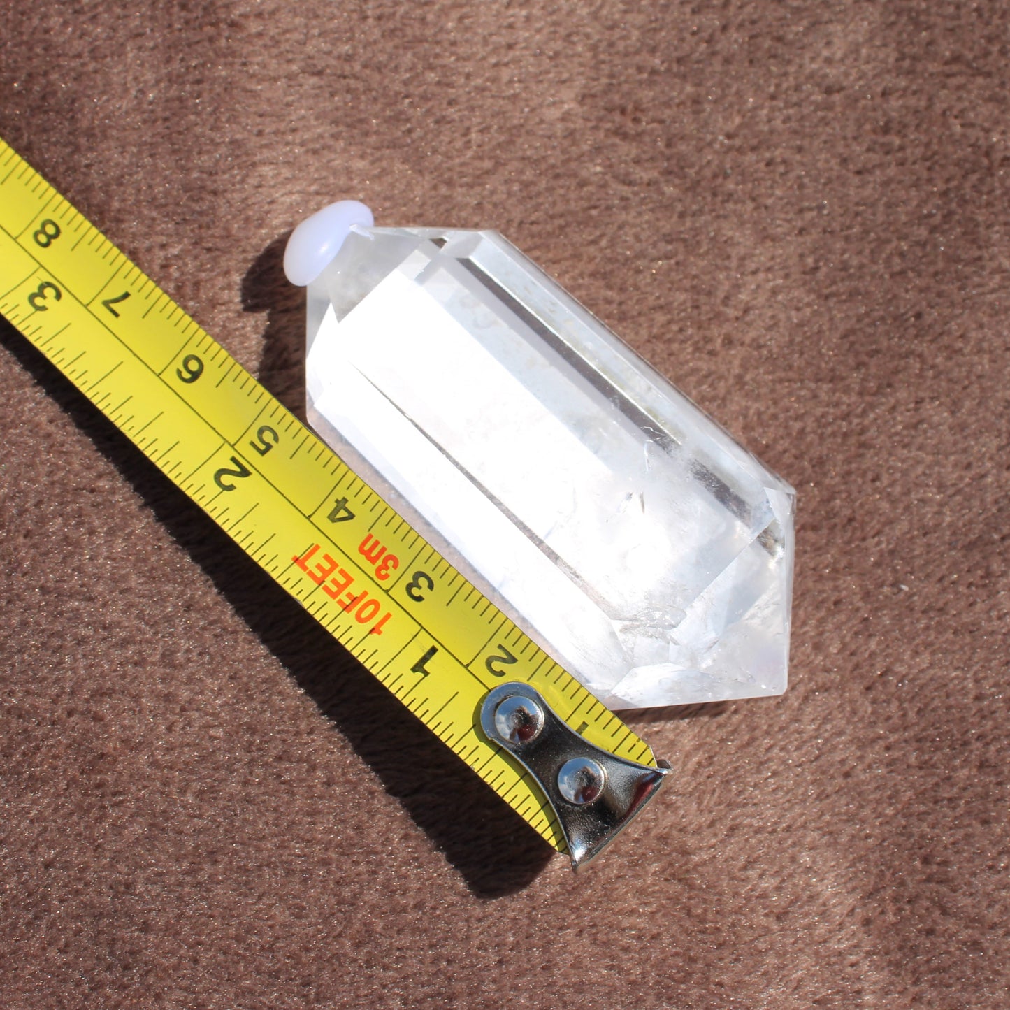 High Quality Clear Quartz crystal measuring about 3 inches on a yellow tape measure