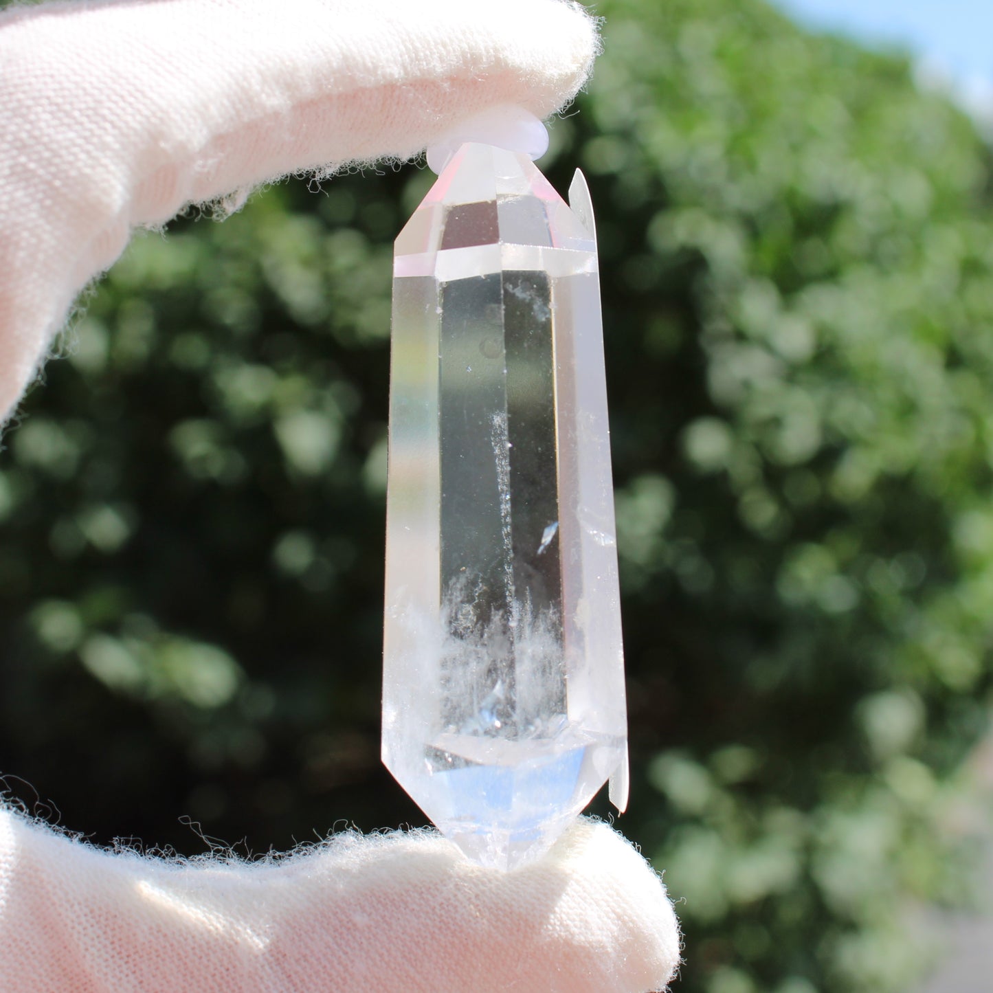 High Quality Clear Quartz crystal held with white gloves outdoors by Different Branches LLC