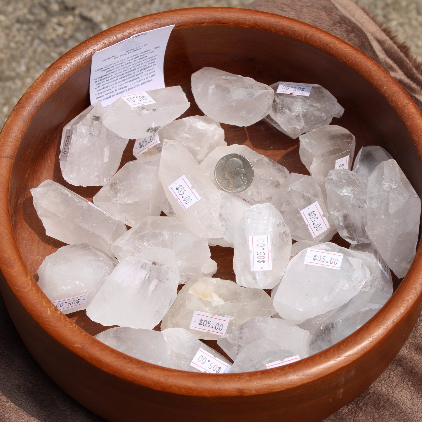 Imperfect quartz raw points displayed in a wooden bowl with pricing labels for sale