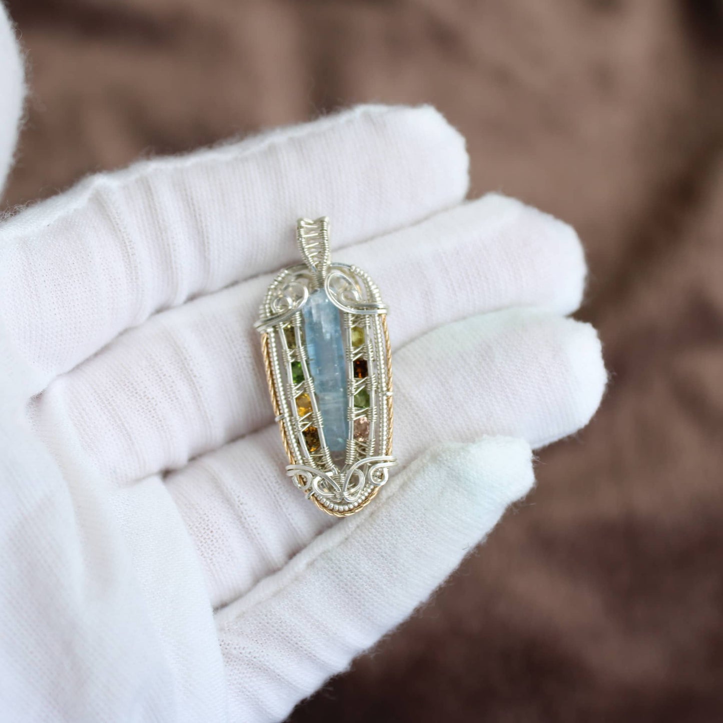 Intricate Kyanite sterling silver pendant held by a hand showcasing its elegant design