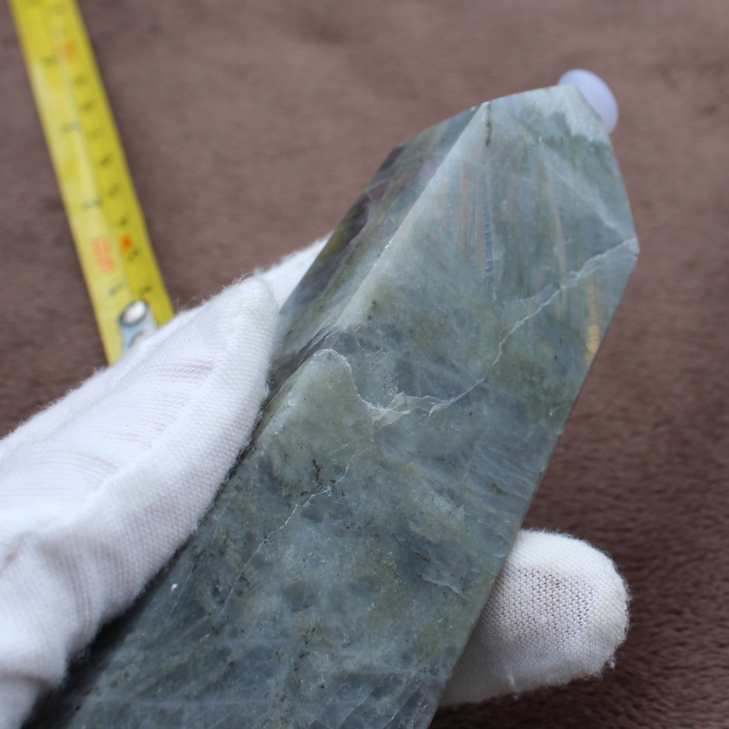 Labradorite Tower crystal held in white-gloved hand showing blue and green iridescent hues