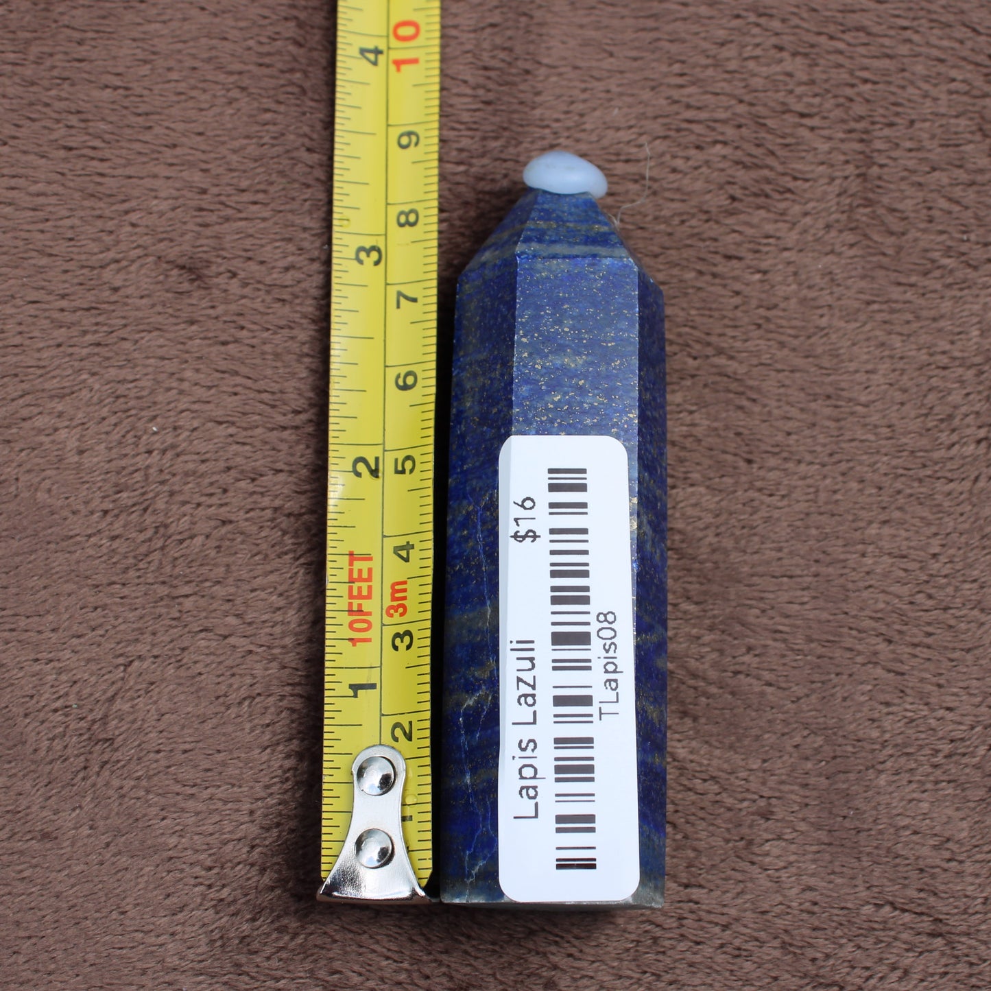 Lapiz Lazuli Tower crystal with deep blue color and gold flecks measured next to a tape measure