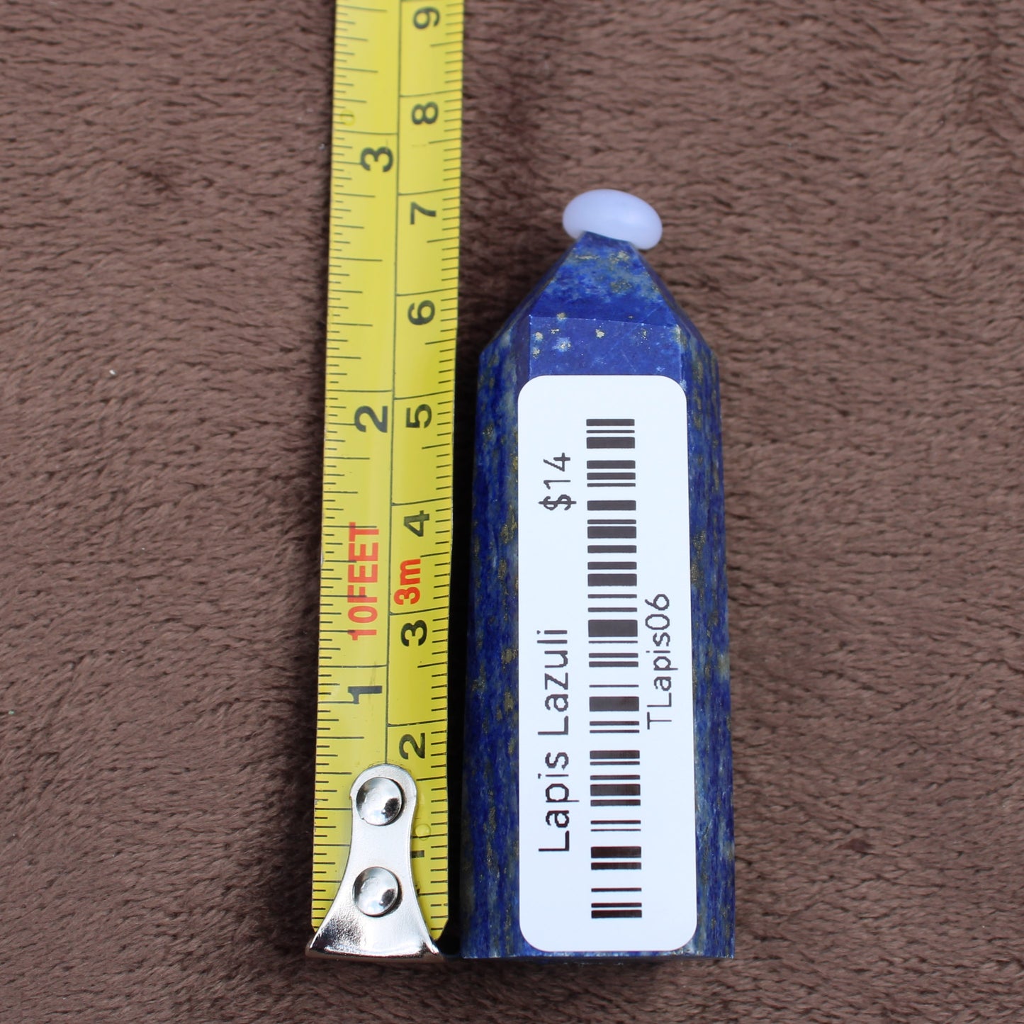 Lapiz Lazuli Tower crystal next to a measuring tape showing its size in inches and centimeters