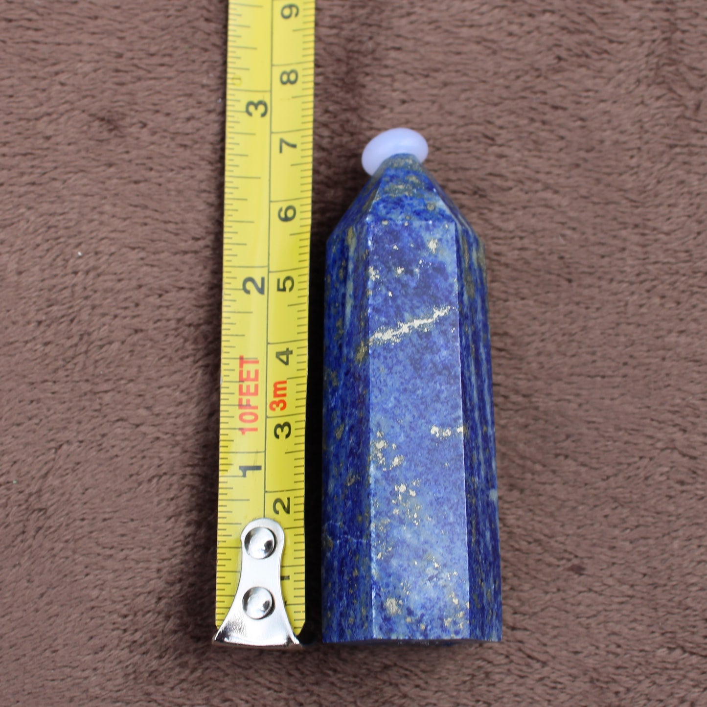 Lapiz Lazuli Tower crystal standing next to measuring tape showing size for Different Branches LLC
