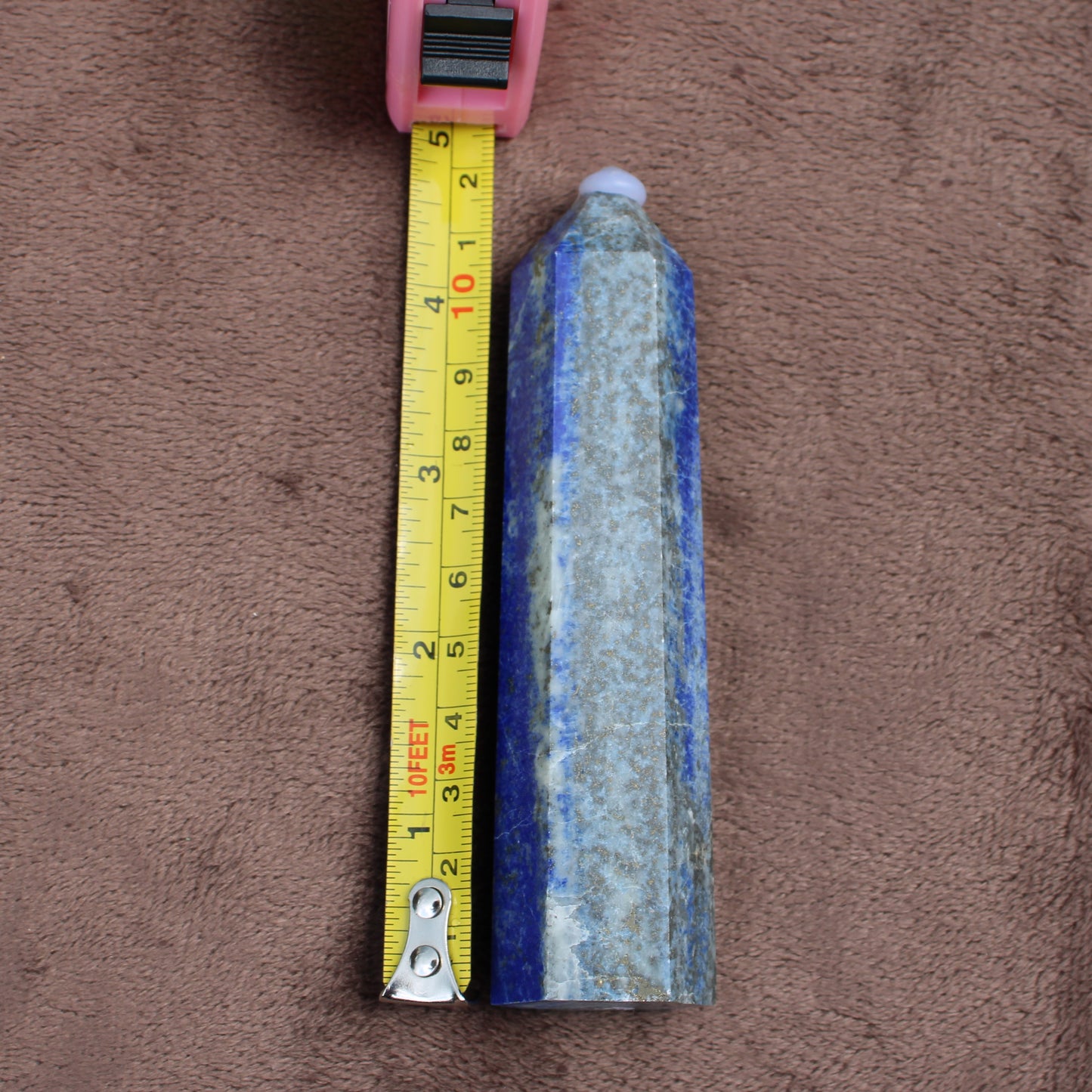 Lapiz Lazuli Tower crystal from Different Branches LLC measuring about 5 inches on a brown background