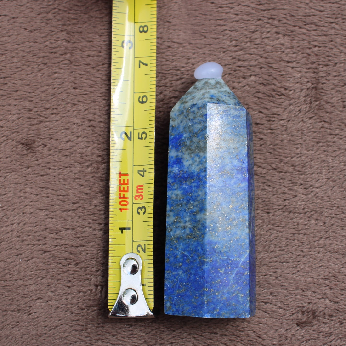 Polished Lapiz Lazuli Tower crystal next to measuring tape showing size by Different Branches LLC