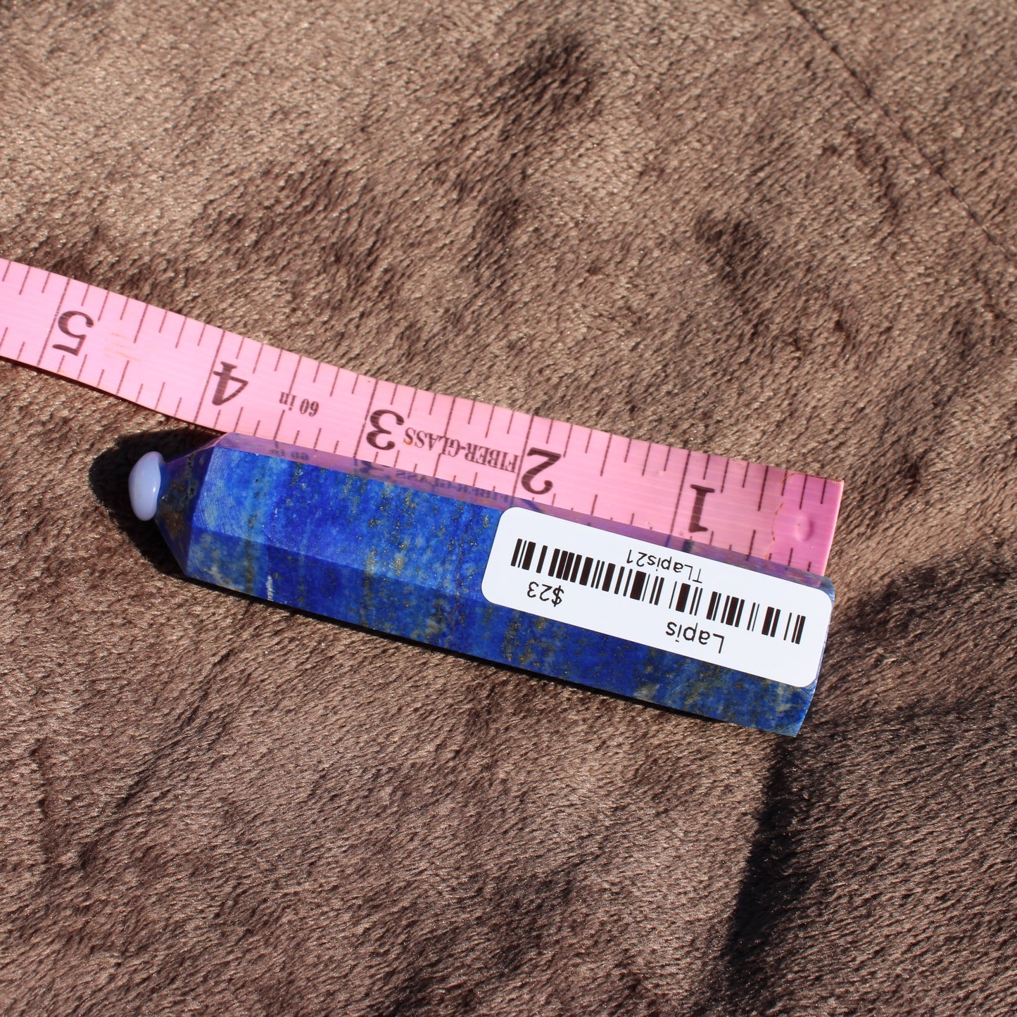 Lapis Tower Collection featuring a polished lapis stone with a smooth finish and measuring tape for size comparison