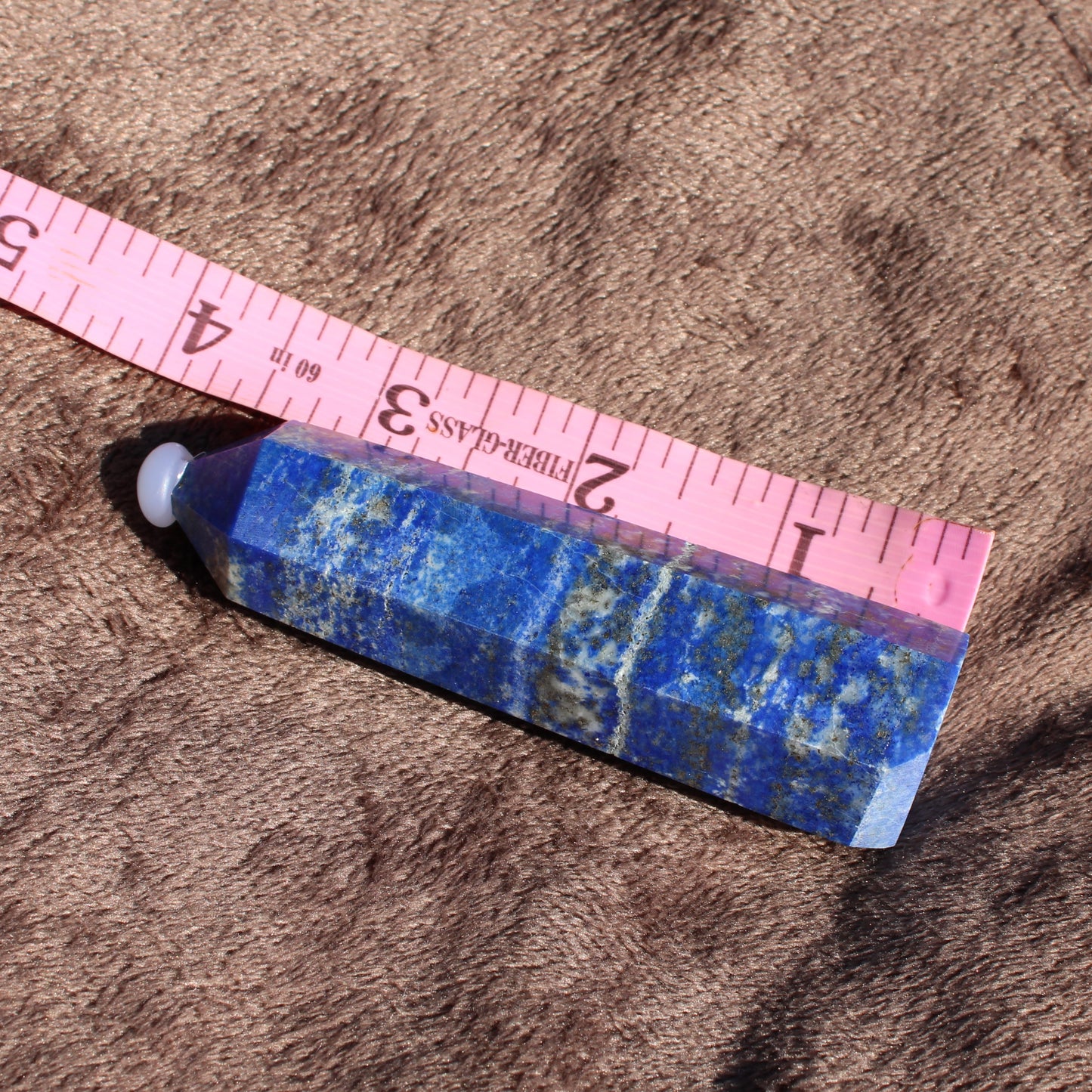 Lapis Tower Collection featuring a polished blue lapis lazuli crystal with measuring tape for size reference