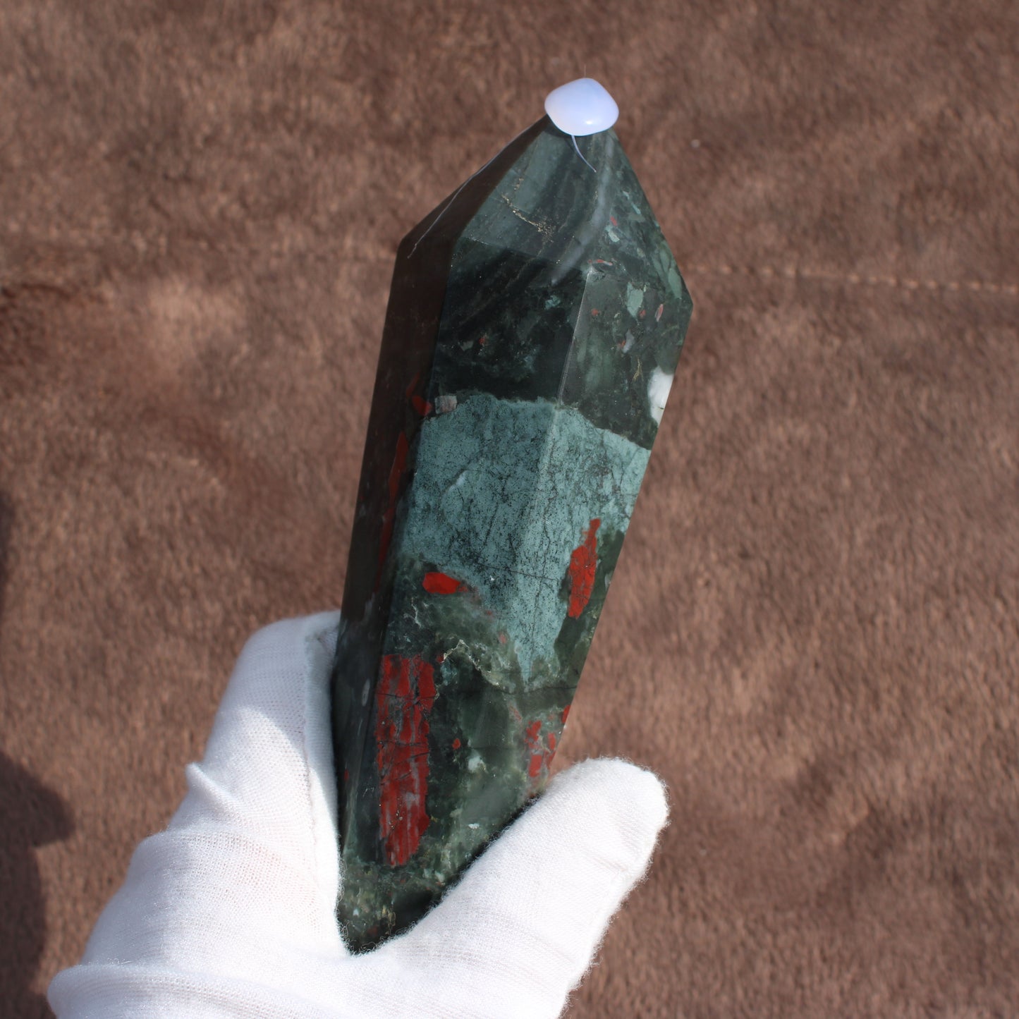 Large Bloodstone Wand held in white gloved hand showing deep green and red crystal with pointed tip