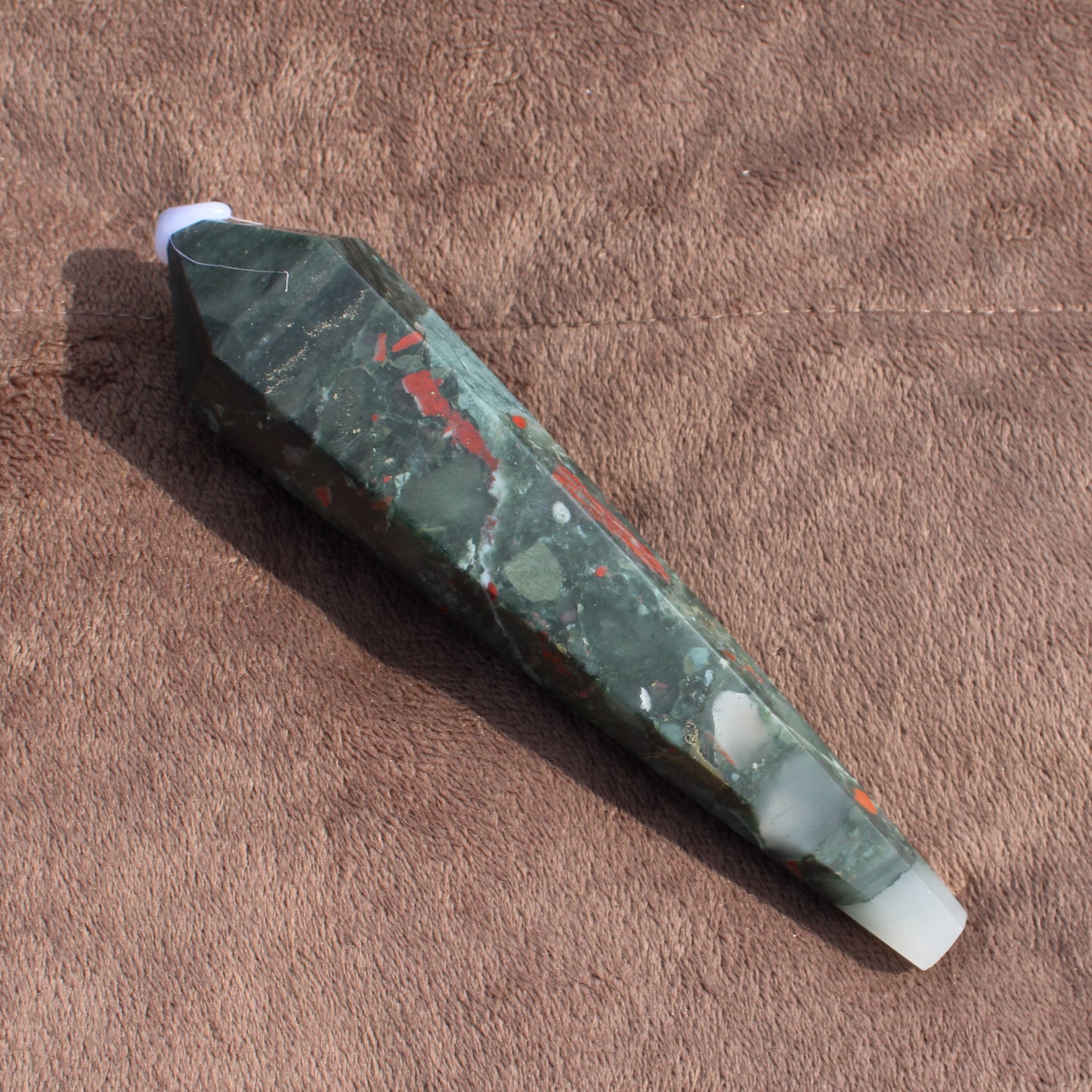 Large Bloodstone Wand crystal with green and red patterns on brown textured background