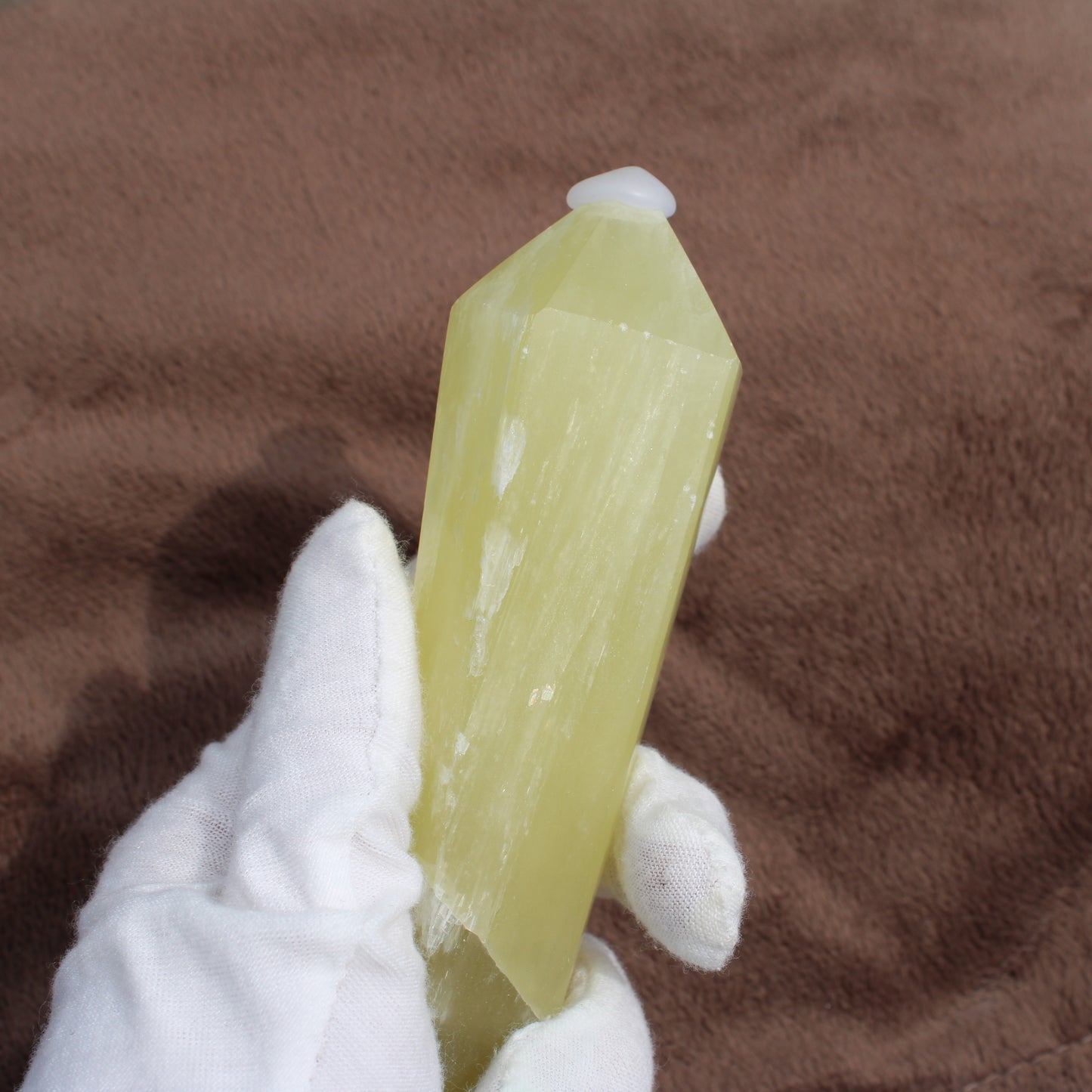 Lemon Quartz Wand held in white glove showing smooth yellow crystal from Different Branches LLC